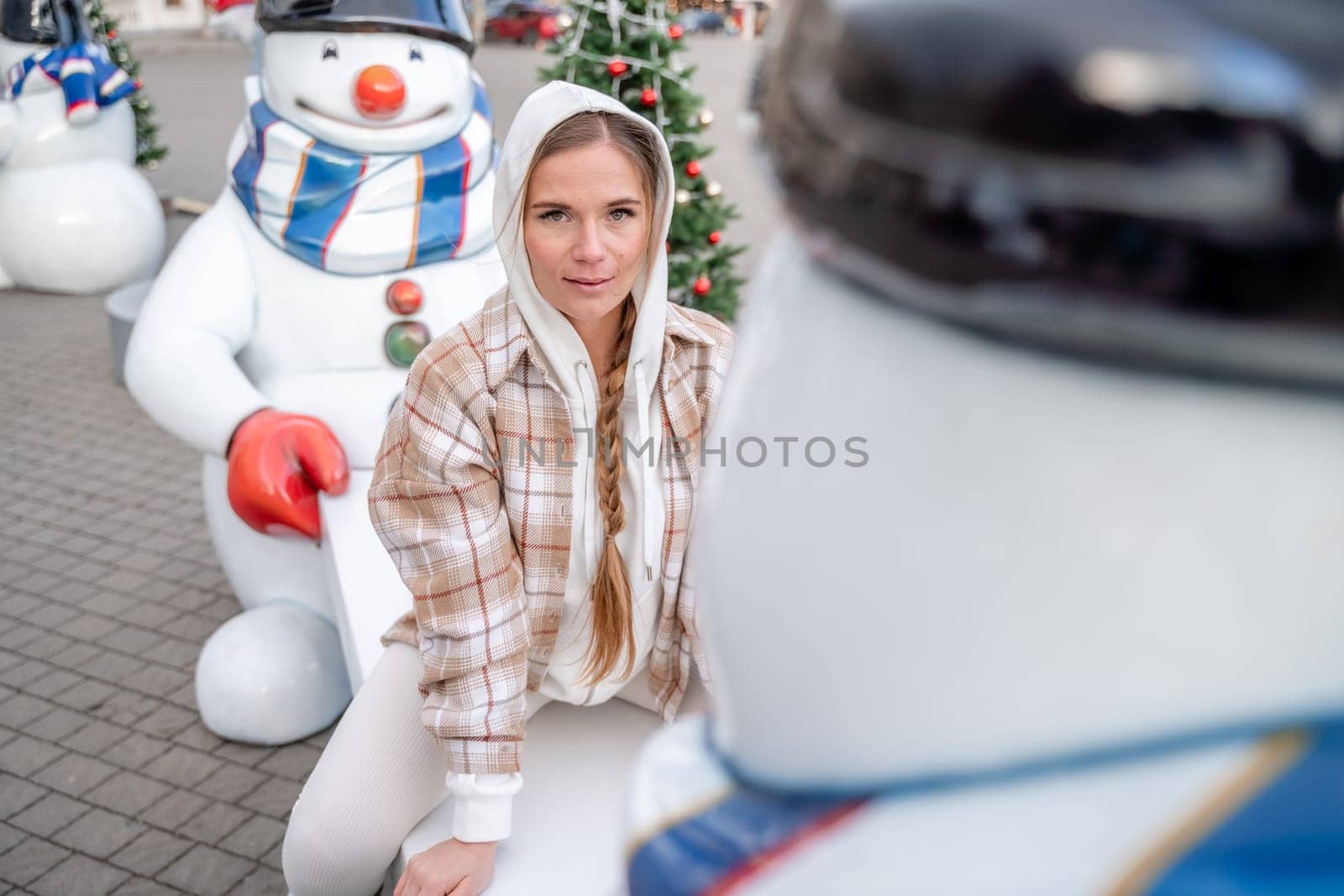 Woman Christmas Square. Close-up of a winter white toy snowman With trees decorated with Christmas tinsel in the background.