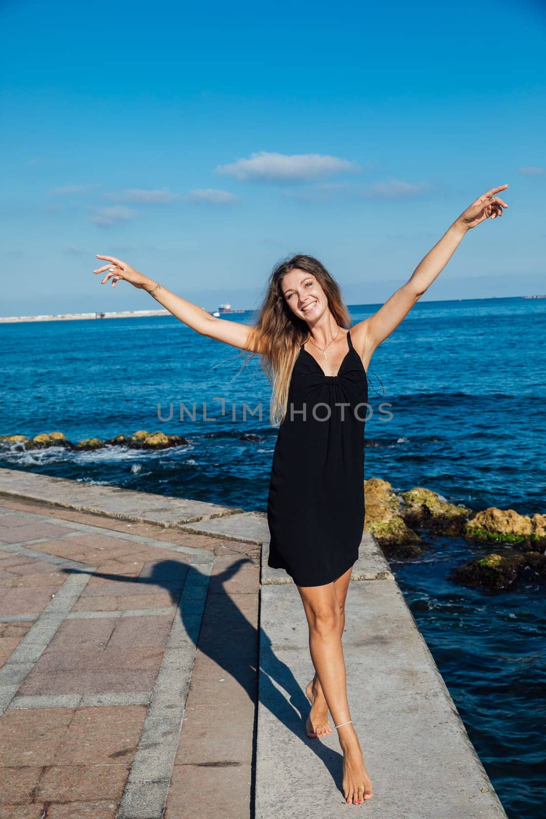 woman in black summer dress on a walk by the sea