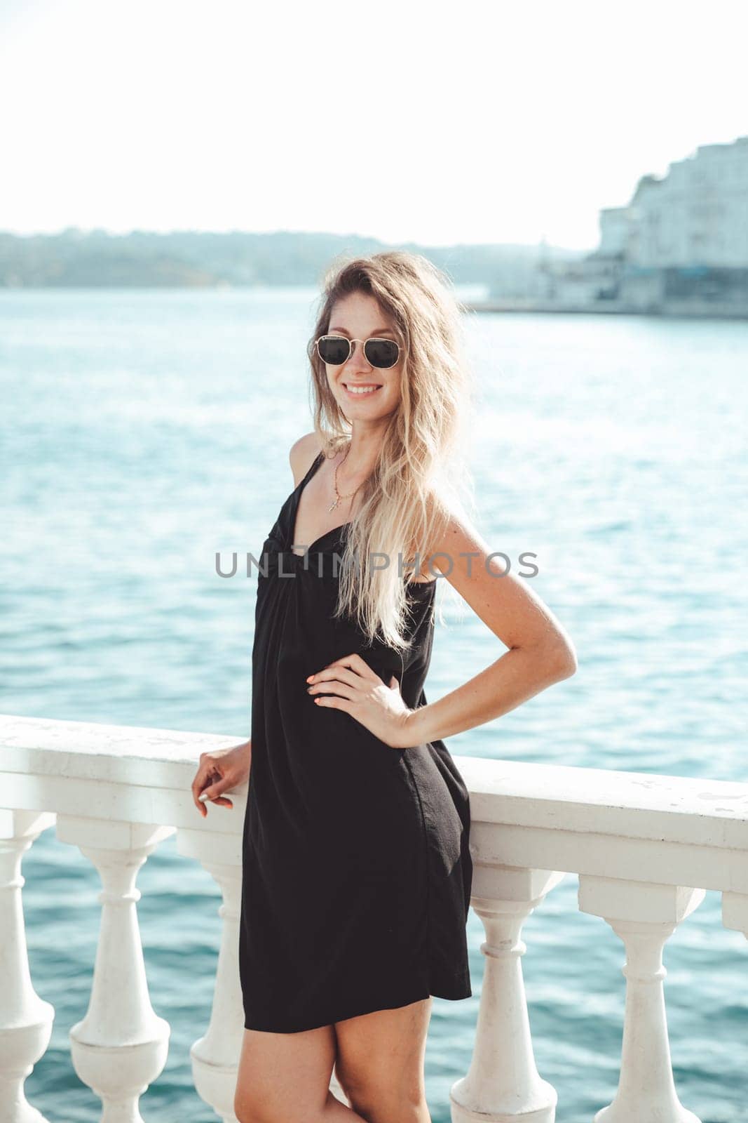 woman in black summer dress on a walk by the sea