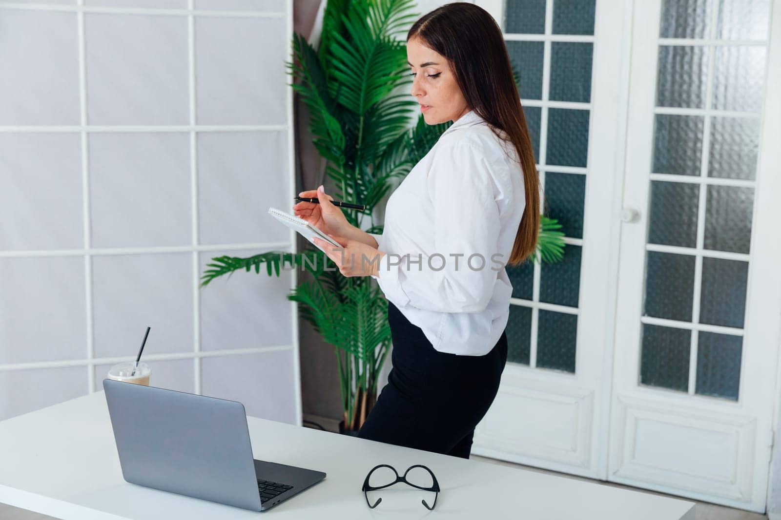 female gardener in glasses using laptop, communicates on internet with customer in home