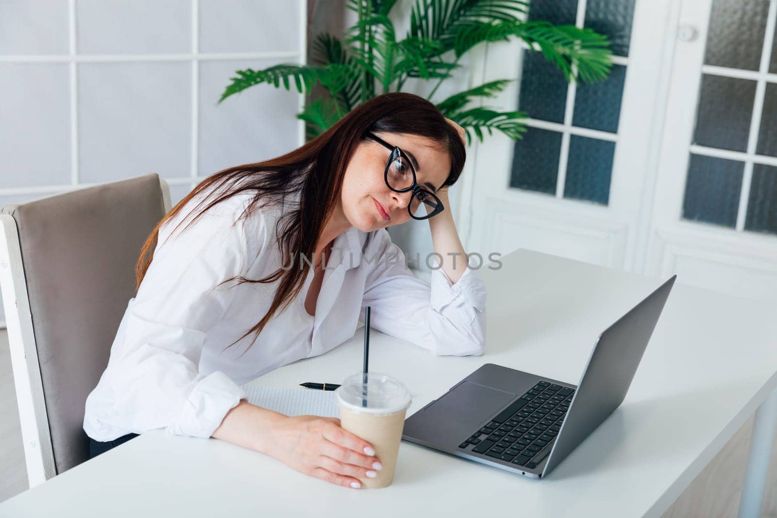 woman tired of working on laptop in office by Simakov
