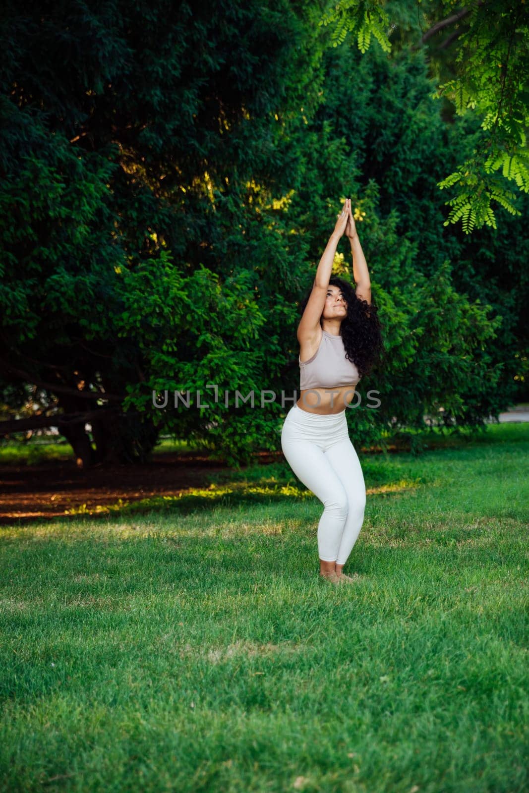 Young brunette asian woman practicing yoga during workout in park by Simakov