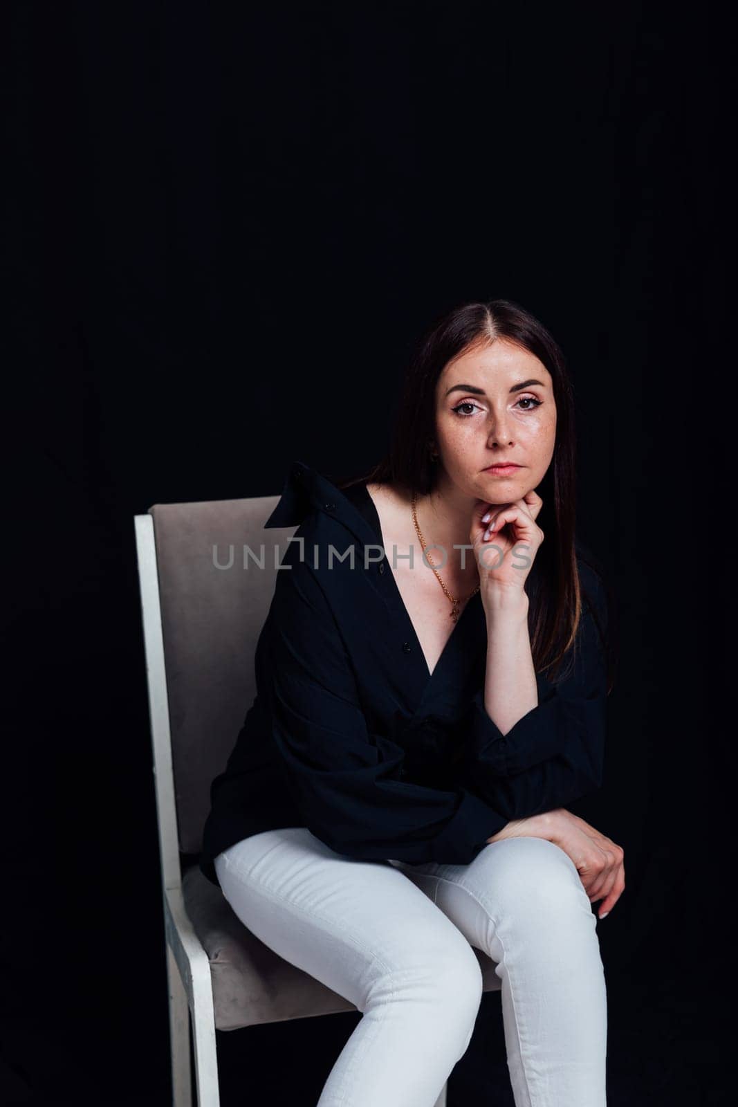 Portrait of beautiful brunette woman in white pants and black shirt by Simakov