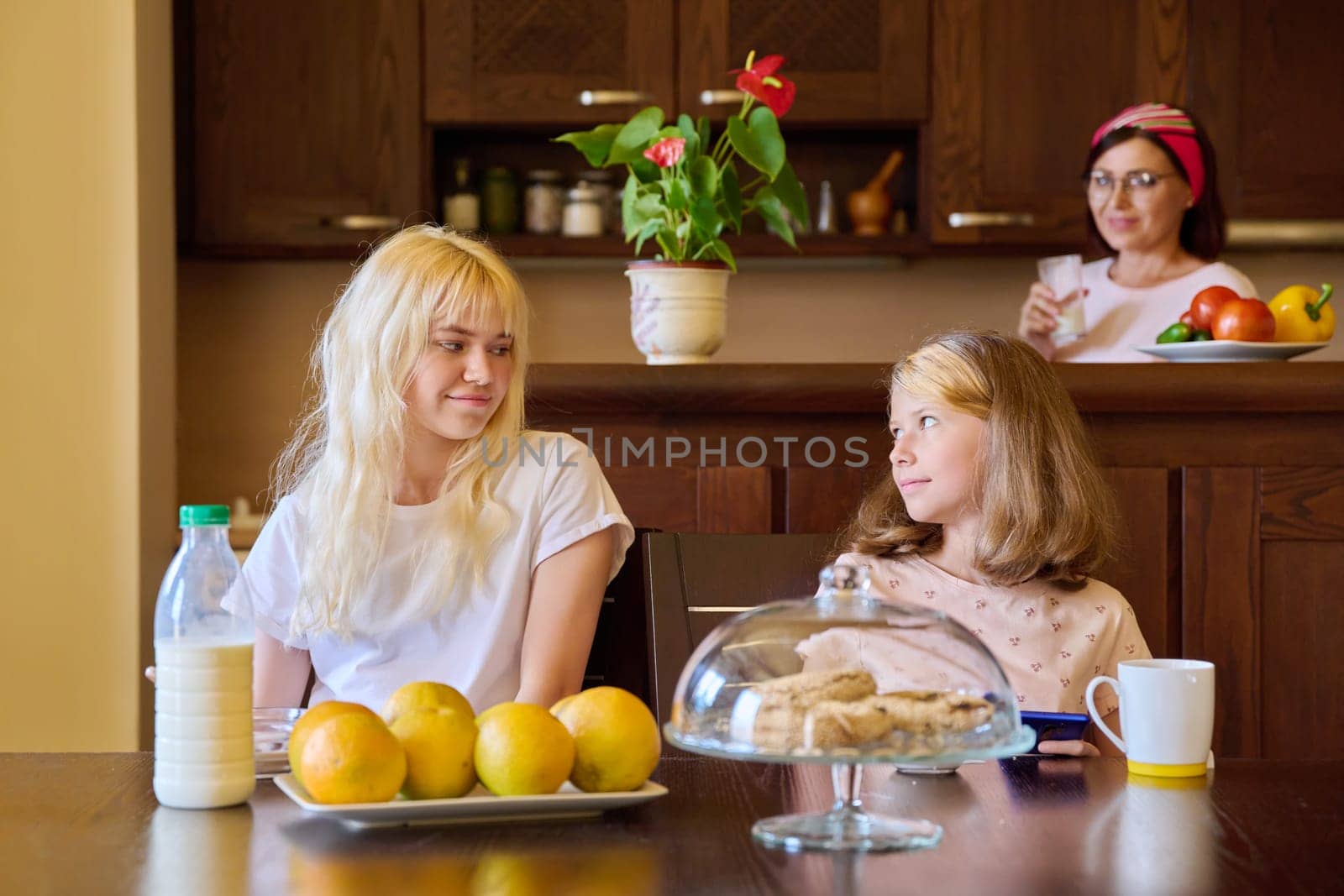 Children two sisters eating at home in the kitchen by VH-studio