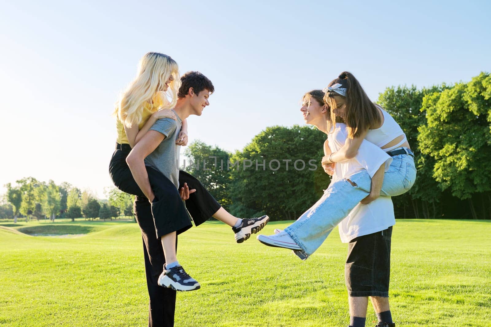 Teenage youth having fun in the park, happy laughing friends. Group of teenagers together on sunny day. Friendship, adolescence, summer, vacation, lifestyle, fun, happiness, holiday, leisure, people