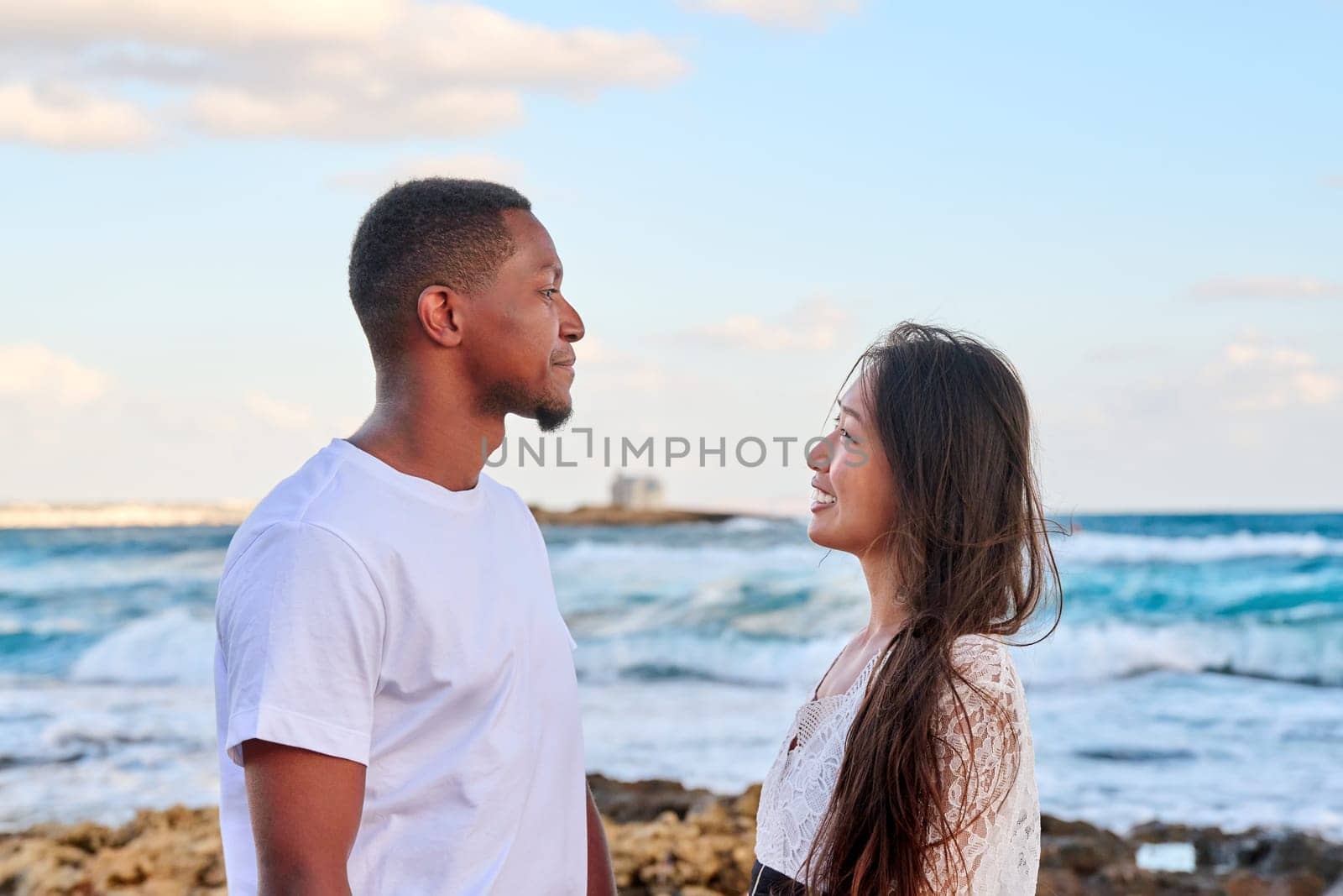 Young beautiful couple looking in the eyes in profile, on the seascape by VH-studio