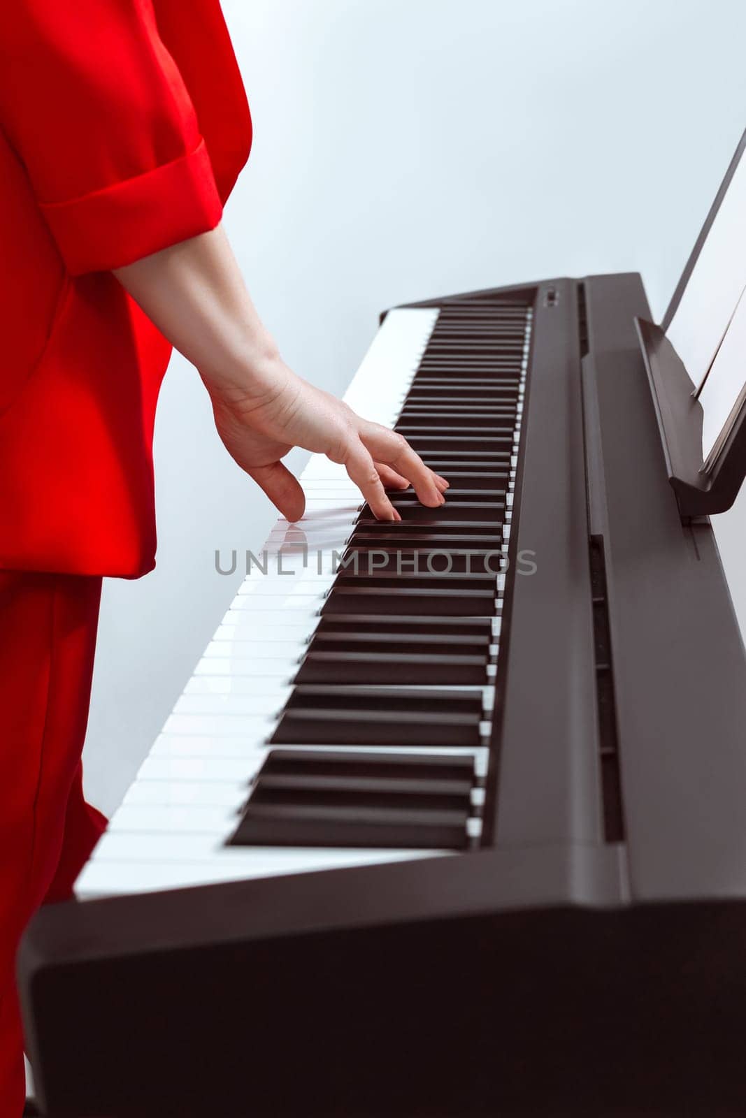 The girl plays the piano with one hand. Pianist's hand on the keys close-up. Partial focus