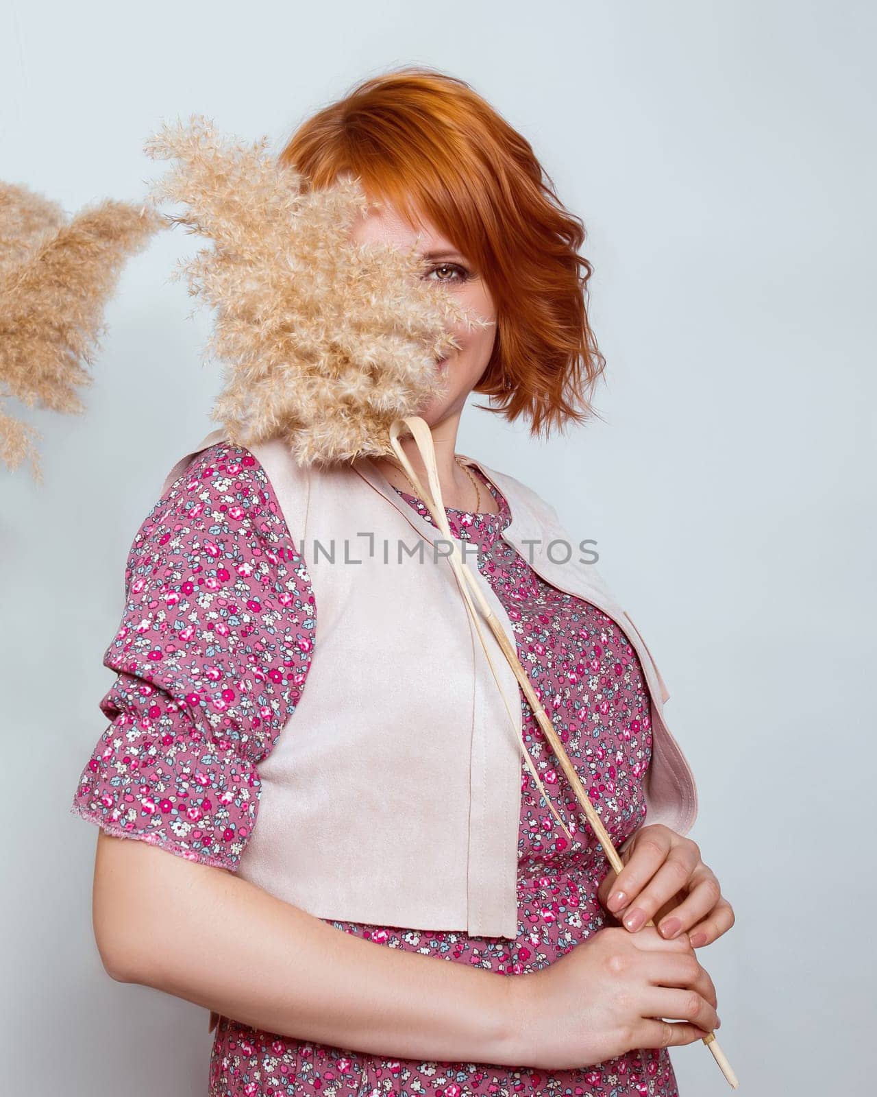 A red-haired woman in a fashionable outfit playfully looks out from behind a reed by ElenaNEL