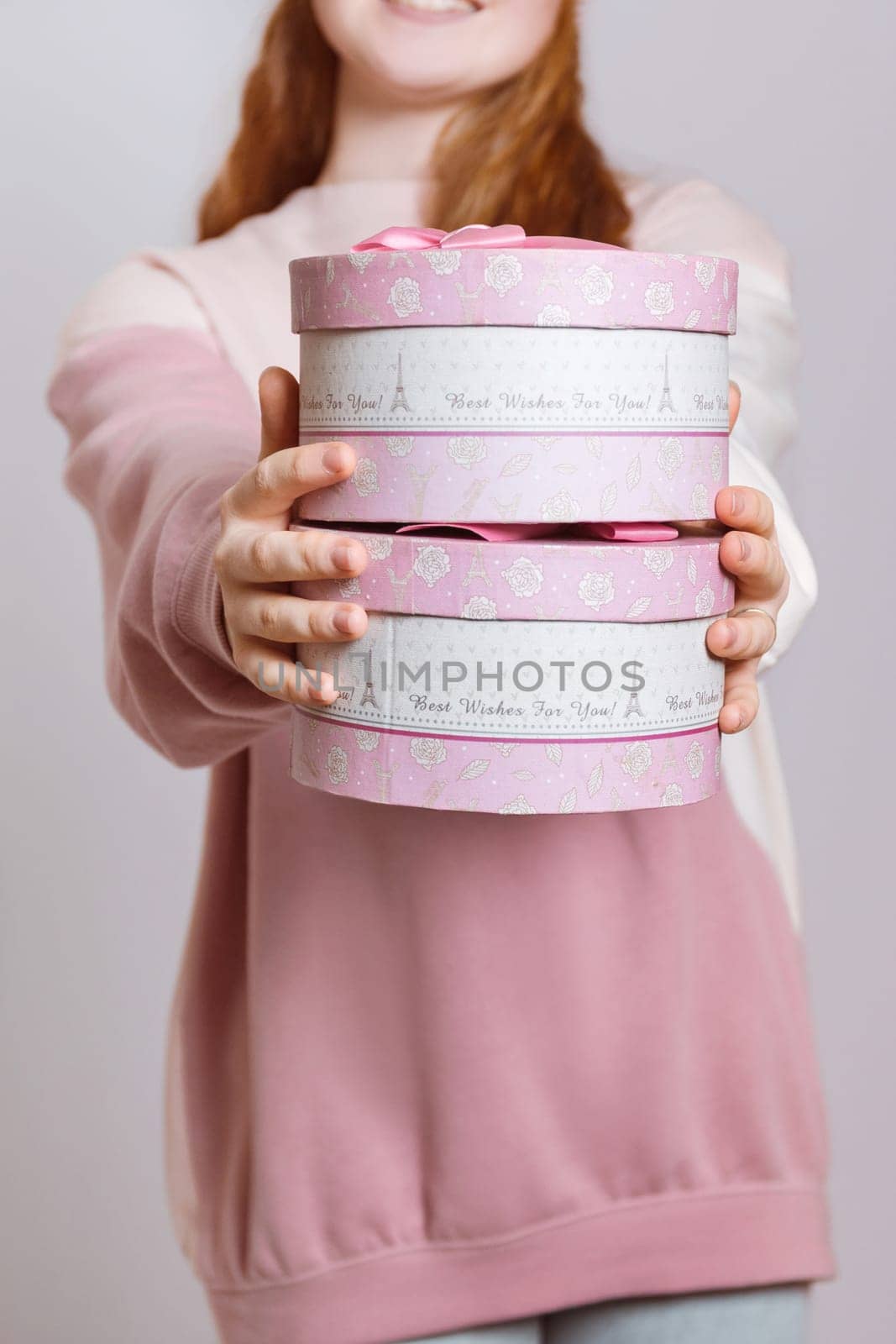 A girl with red hair holds out gift boxes