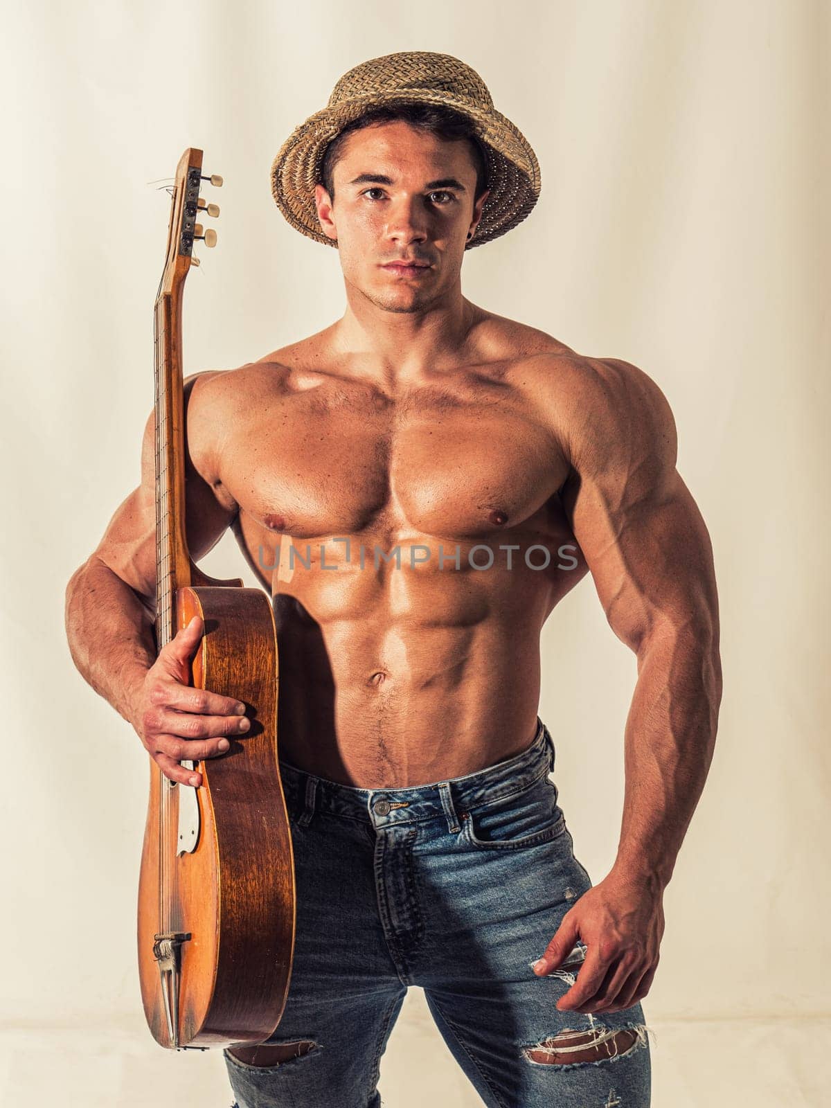 Topless handsome muscular young man playing guitar by artofphoto