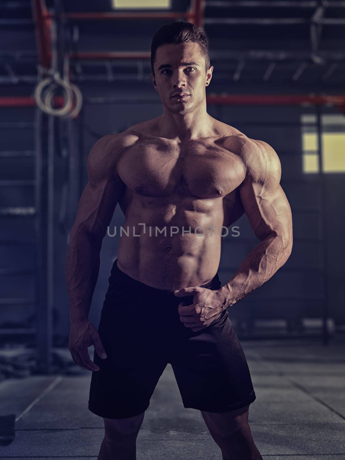 Muscular, shirtless young man resting in gym during workout by artofphoto