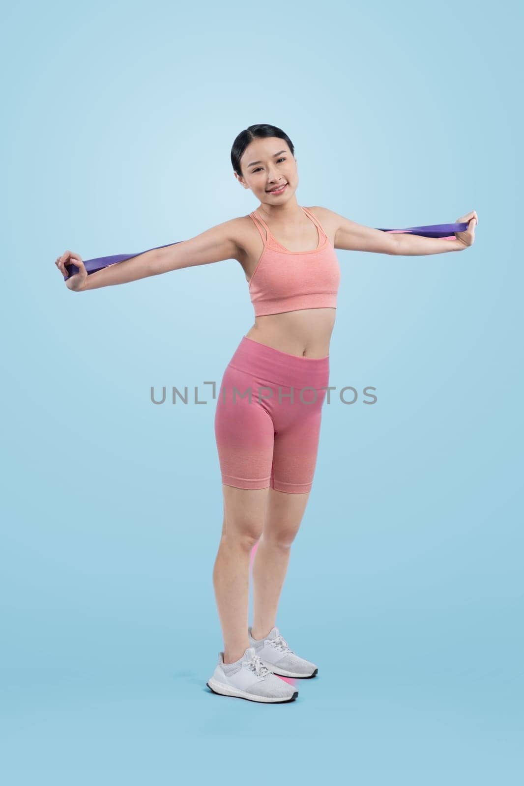 Vigorous energetic woman in sportswear portrait stretching resistance sport band. Young athletic asian woman strength and endurance training session workout routine concept on isolated background.