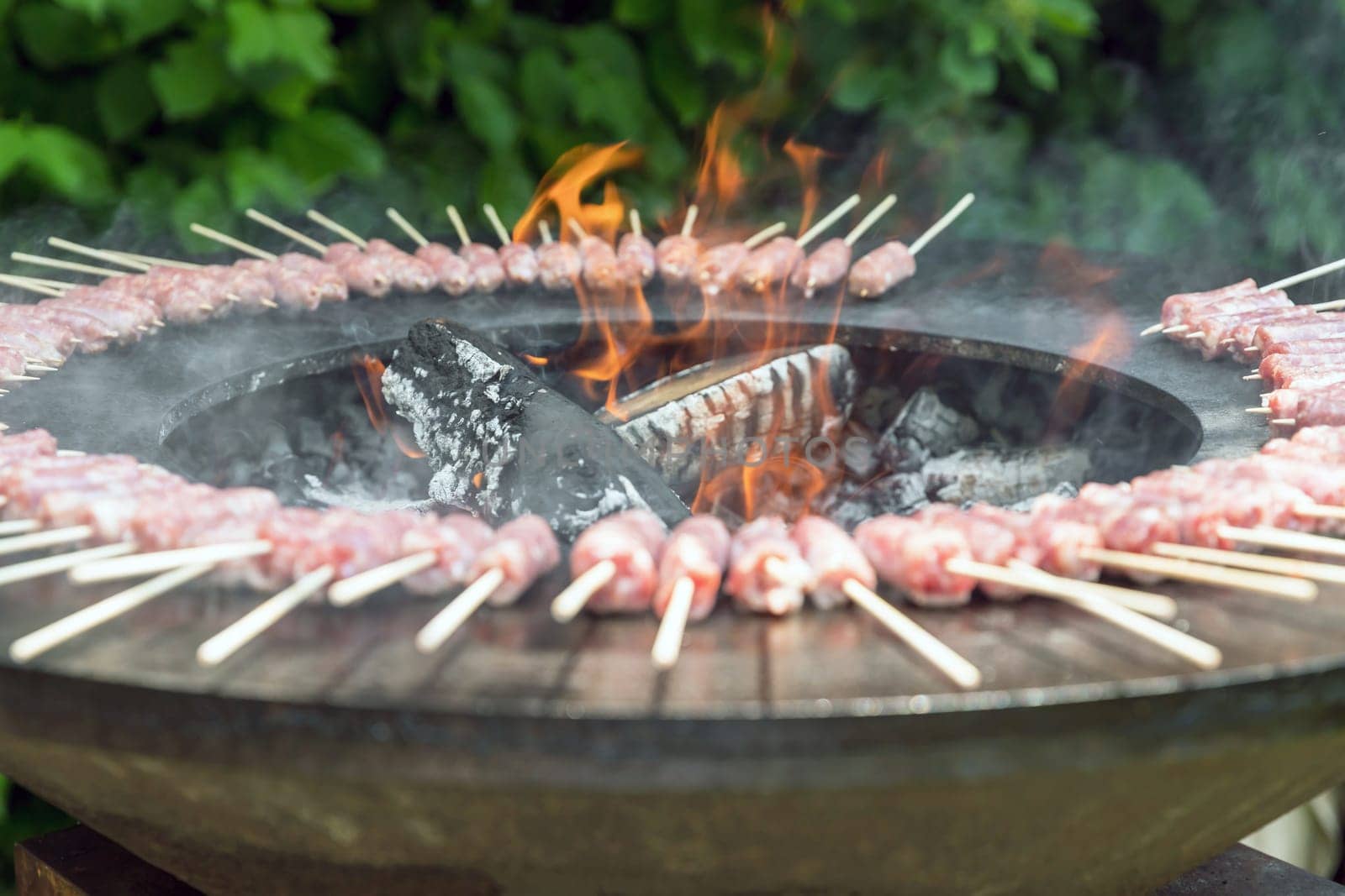 Sausage cooking on a wood brazier. This new concept enhances the advantages of cooking barbecue on a wood brazier.