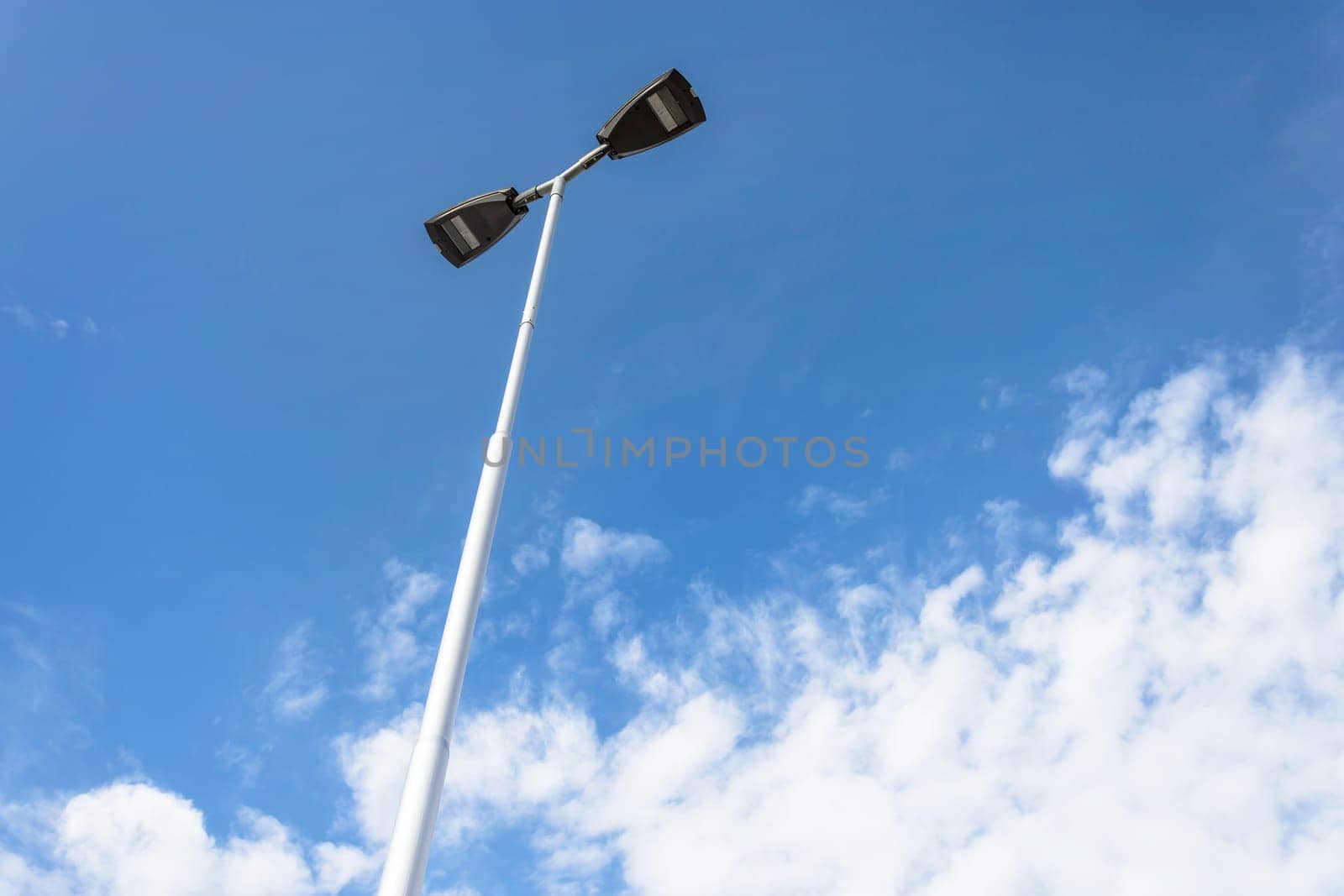 LED lantern for street lighting. Modern street lamp on a metal pole against the blue sky with white clouds. Modern LED lamp street lighting.