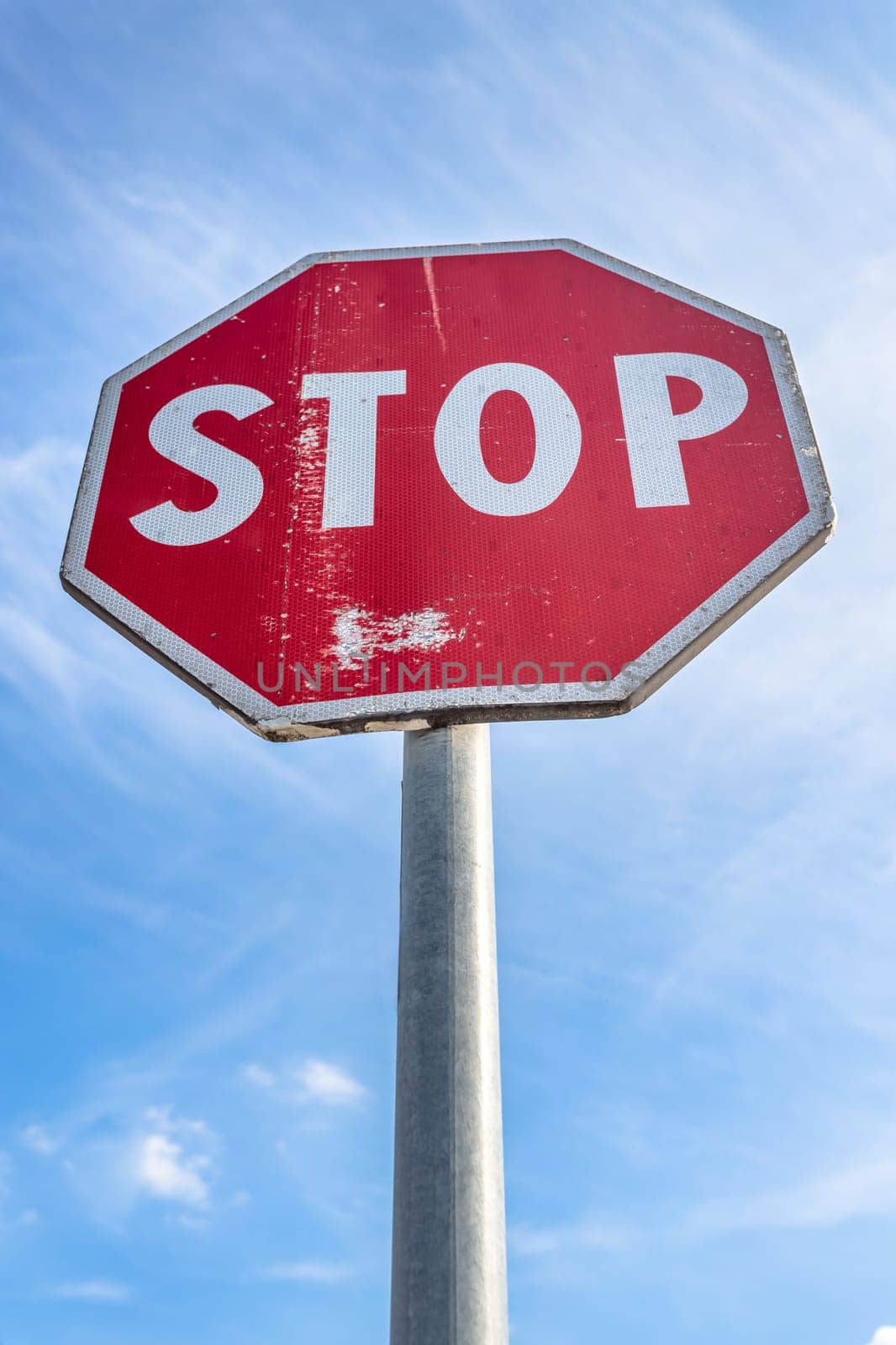 Stop sign against a blue sky with white clouds. Bottom view.