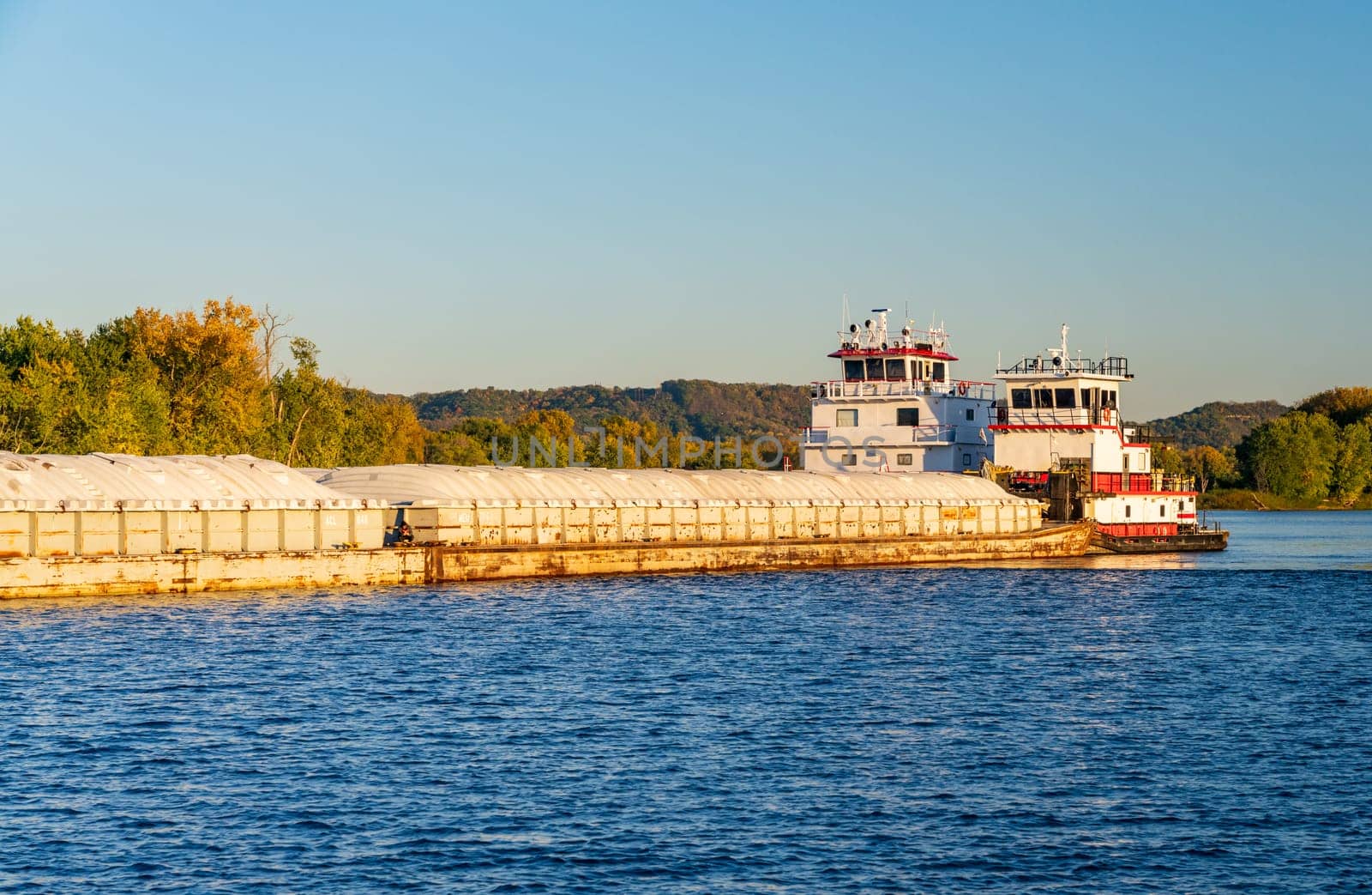 Large river barge on Upper Mississippi being pushed by pair of tugs by steheap