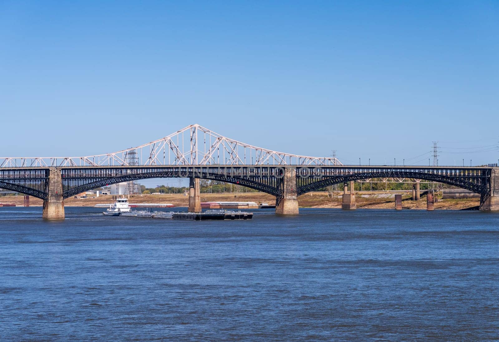 Powerful pusher tugboat with barges of petroleum products under Eads Bridge in St Louis, Missouri