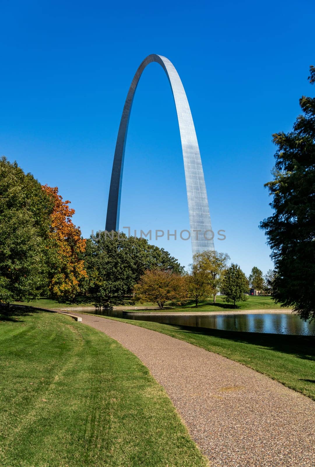 View across green lawn of National Gateway Park with lake to Gateway Arch in St Louis Missouri