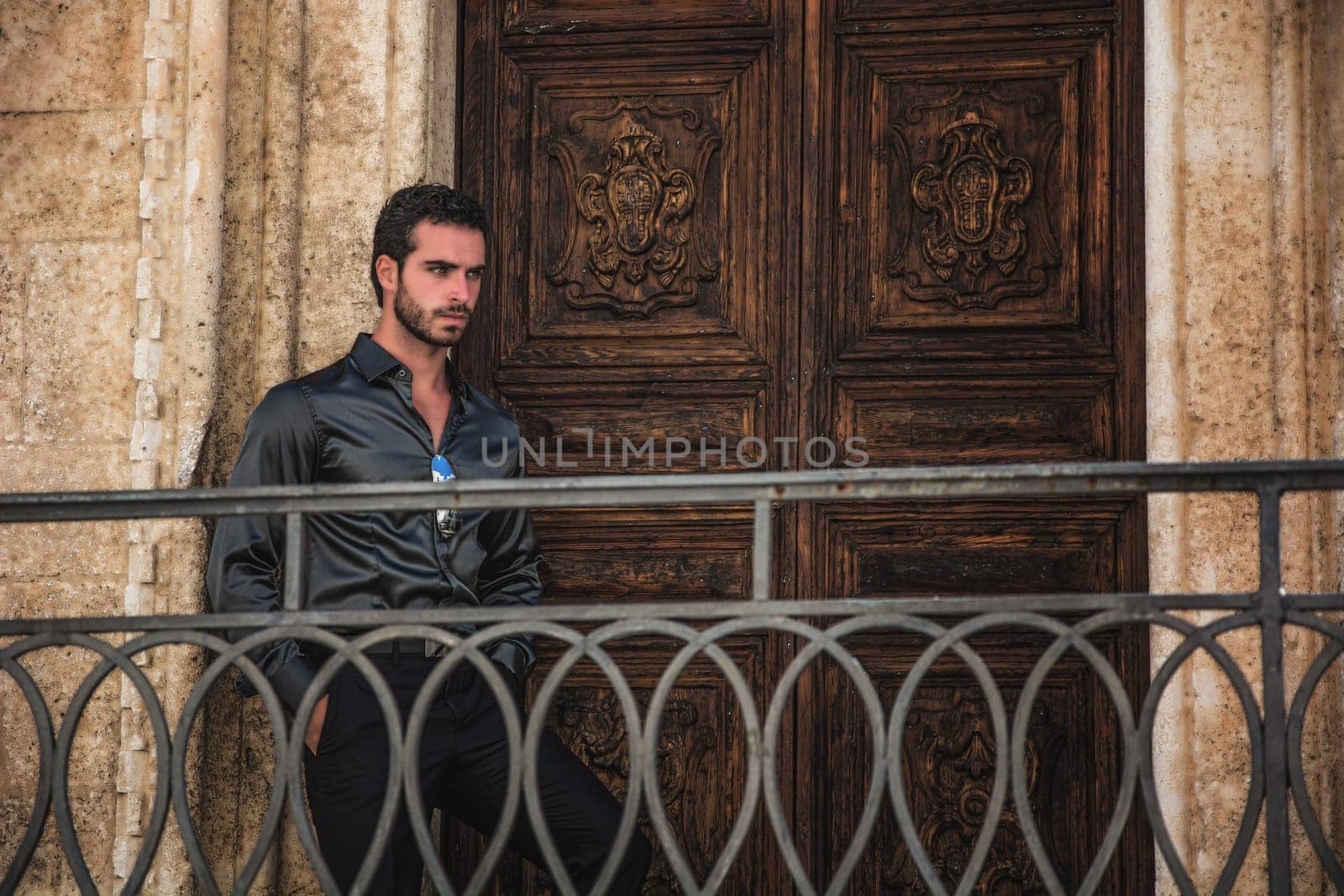 A man standing in front of a wooden door. The Mysterious Man at the Enchanted Wooden Door and Behind a Metal Hand-Rail