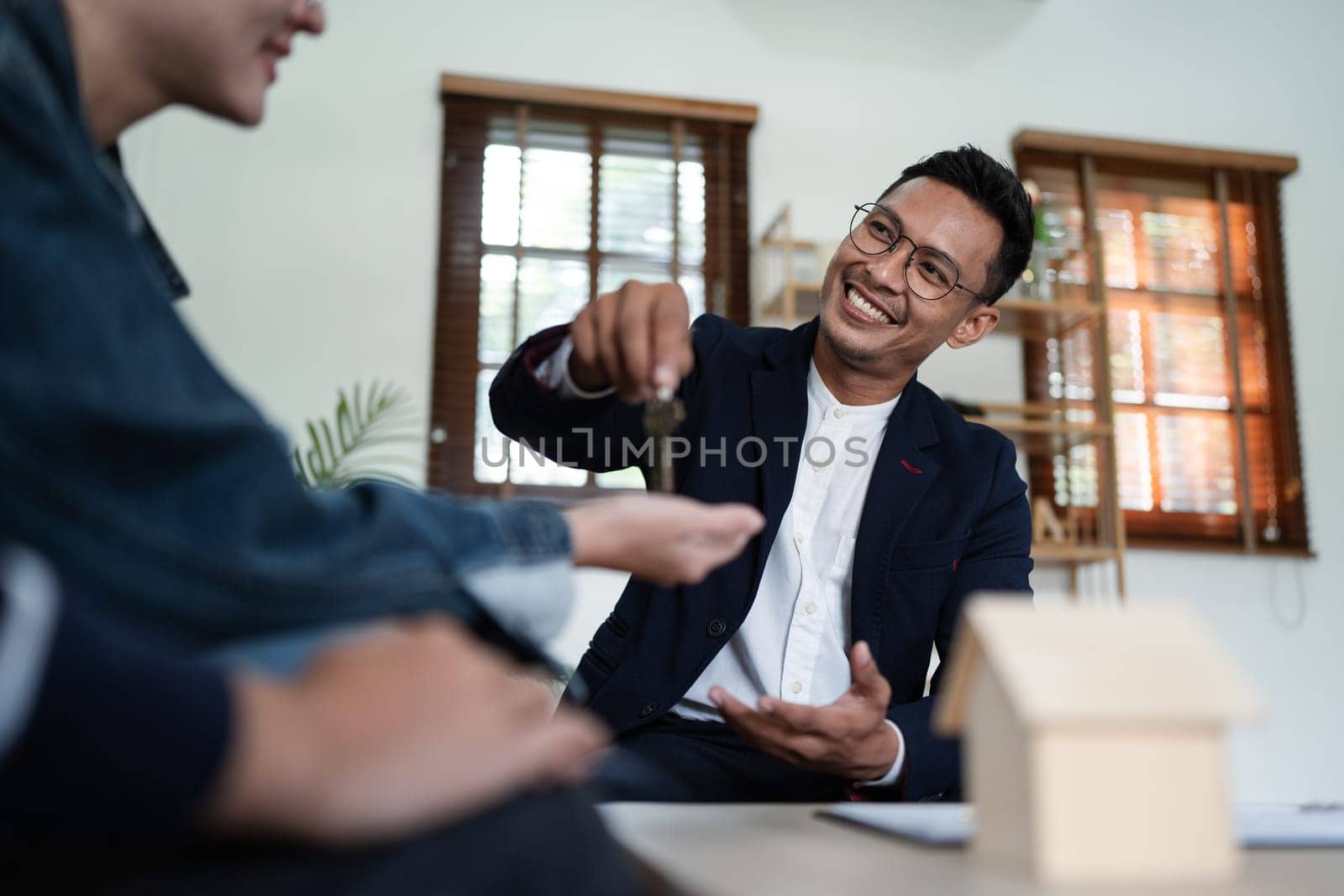Happy real state agent giving new house key to a young couple. Real estate concept by itchaznong