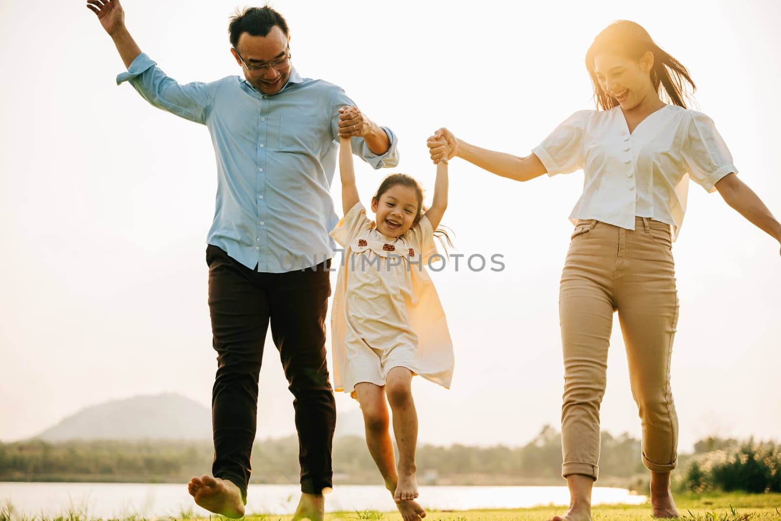 Asian family walking and holding hands in a beautiful springtime park by Sorapop