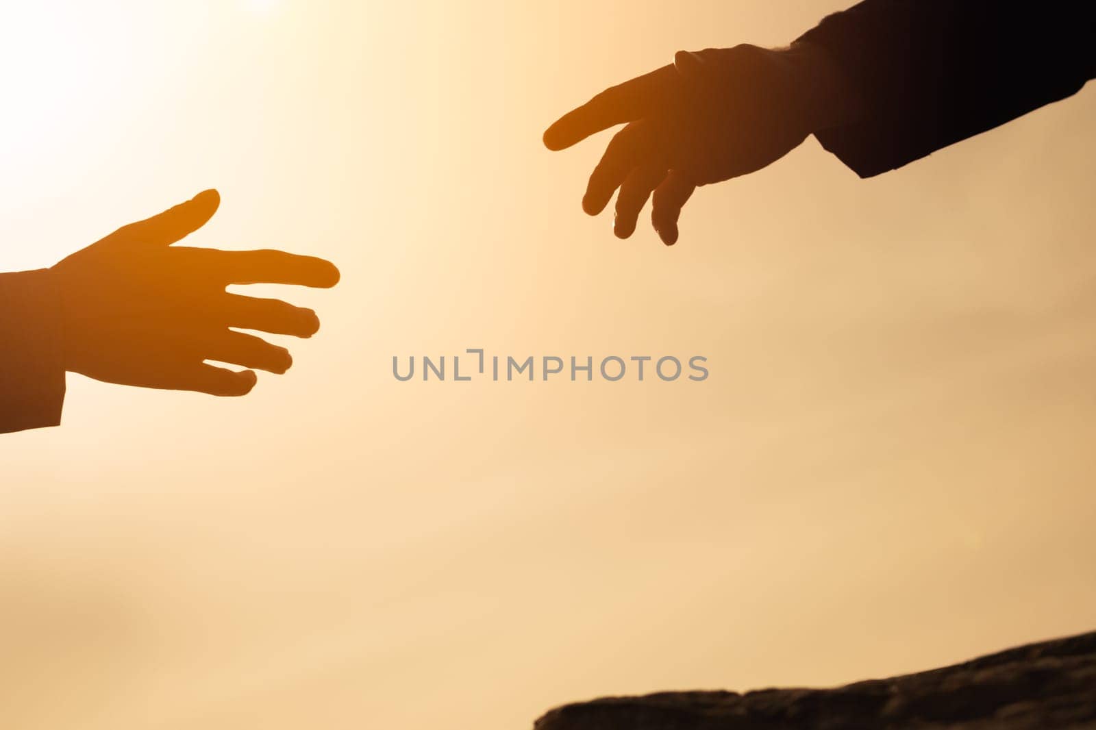 silhouette of hands on the mountain, a man gives a hand to a girl on a mountain, the concept of mutual assistance, motivation for success, place for an inscription. Helping hand. High quality photo