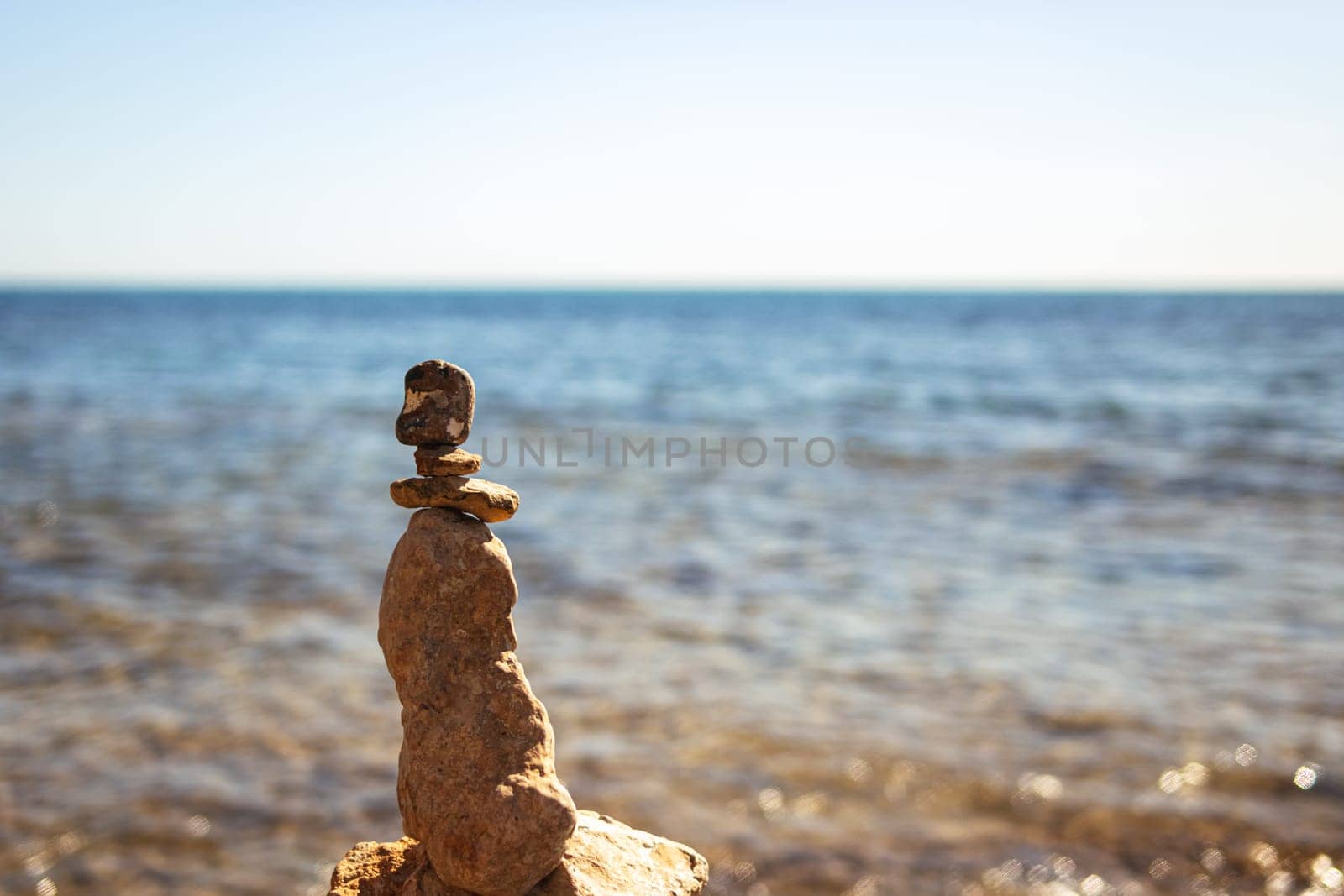 Pyramid of sea pebbles on a sunny sandy beach. The concept of life balance and harmony on the right there is a place for an inscription. High quality photo