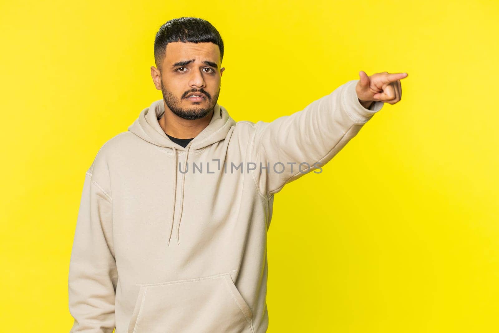 Get out of here. You are fired. Irritated Indian man pointing finger away asking to leave him alone, strict boss firing, conflict, quarrel. Arabian Hindu guy isolated on yellow background indoors