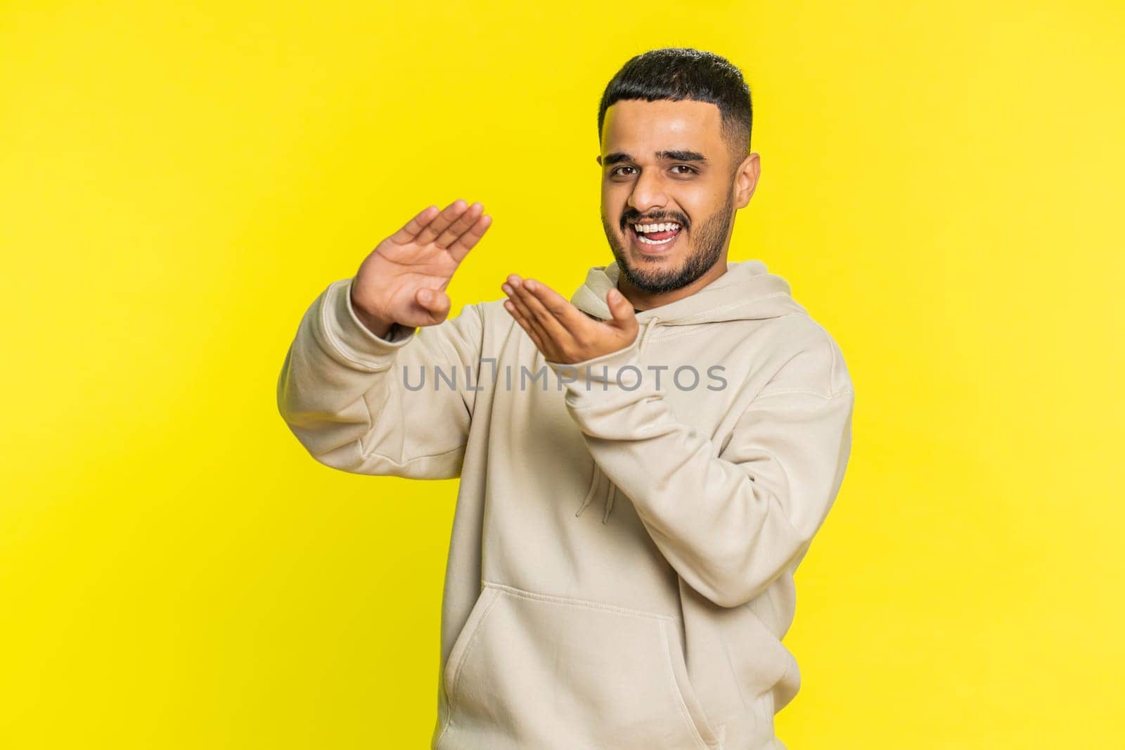 Indian man showing wasting throwing sharing money around, more tips, big profit, winning lottery jackpot, successful shopping payment purchase cashback. Arabian Hindu guy isolated on yellow background