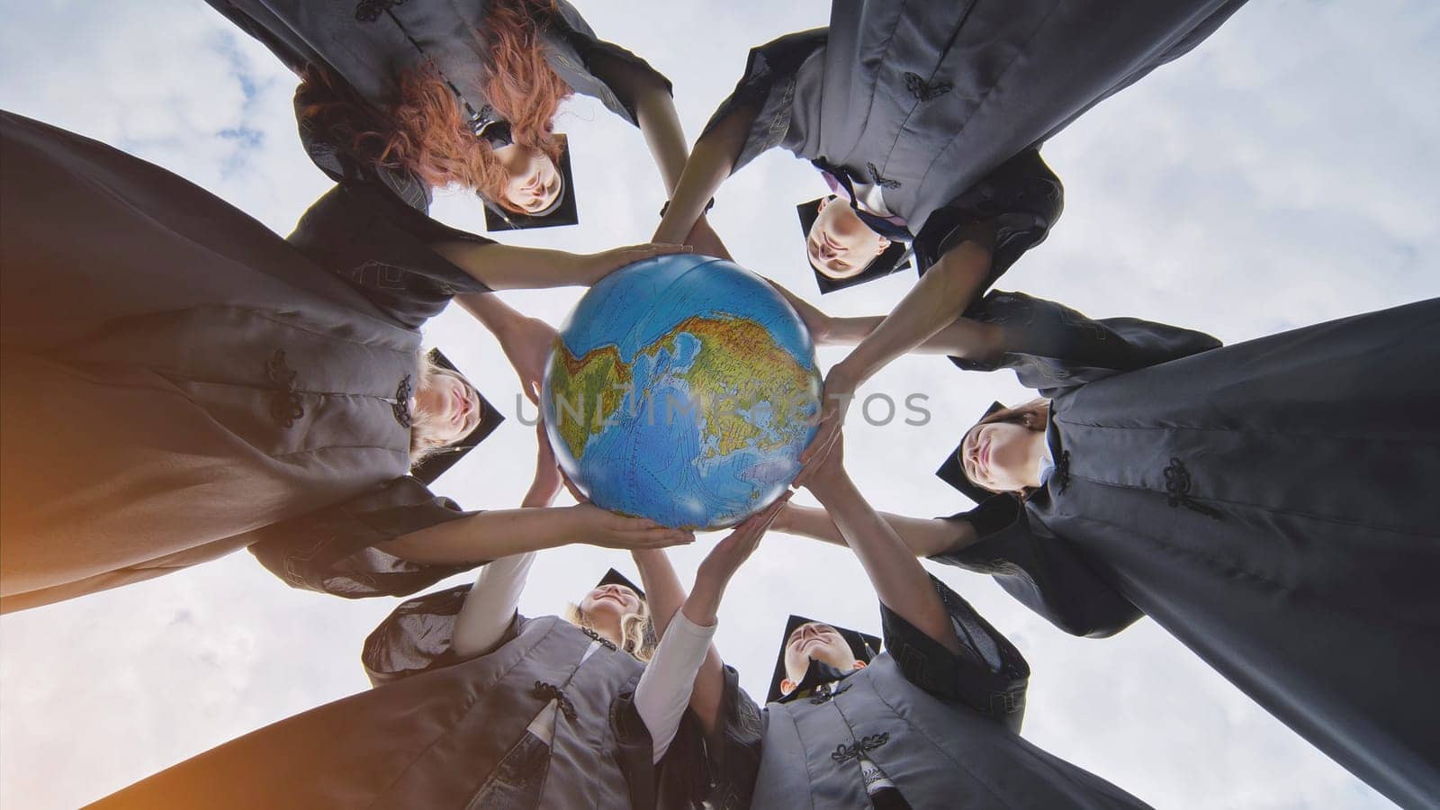 Graduating students twirl a geographic globe of the world in their hands