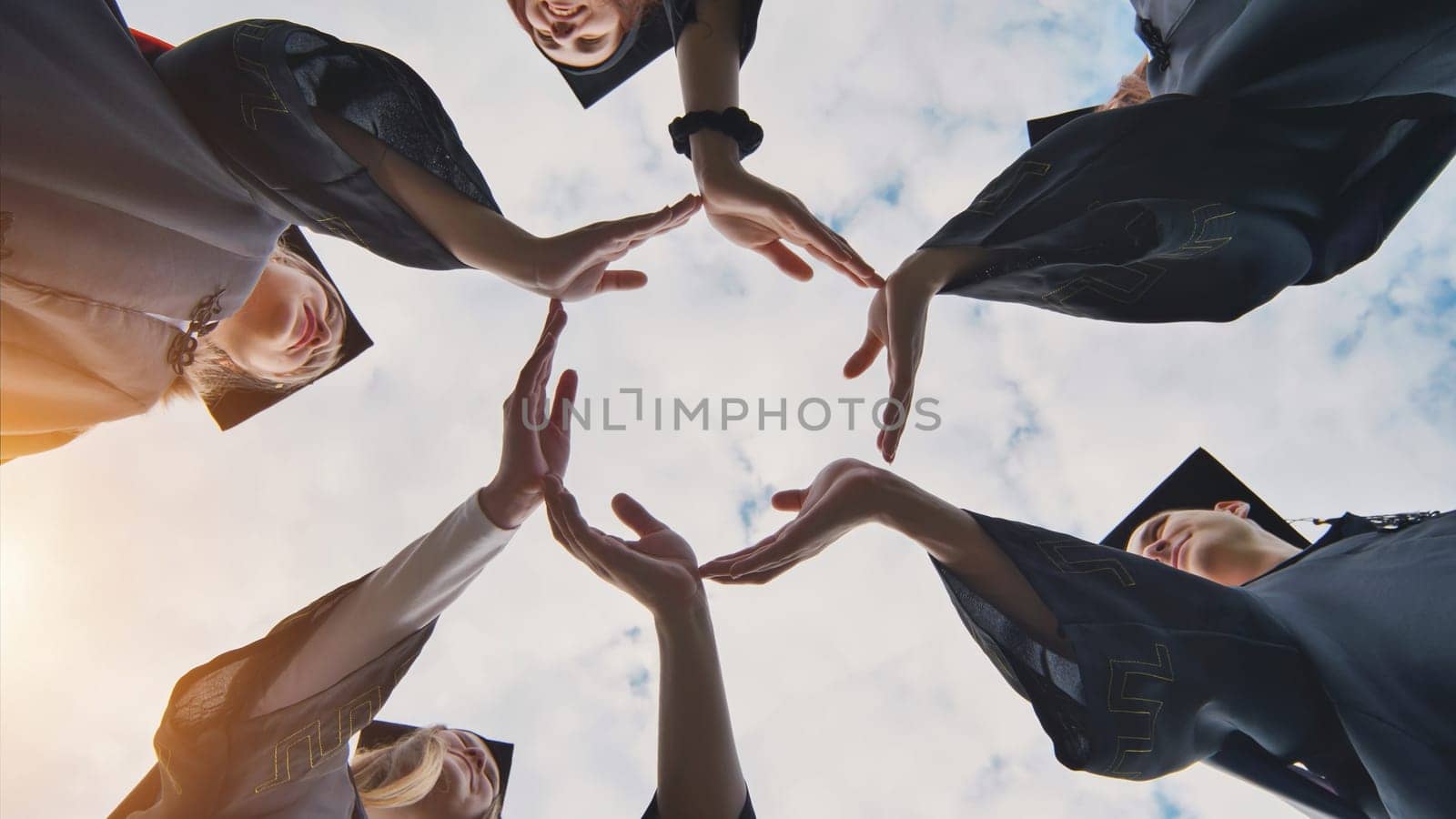 College graduates make a circle of their hands