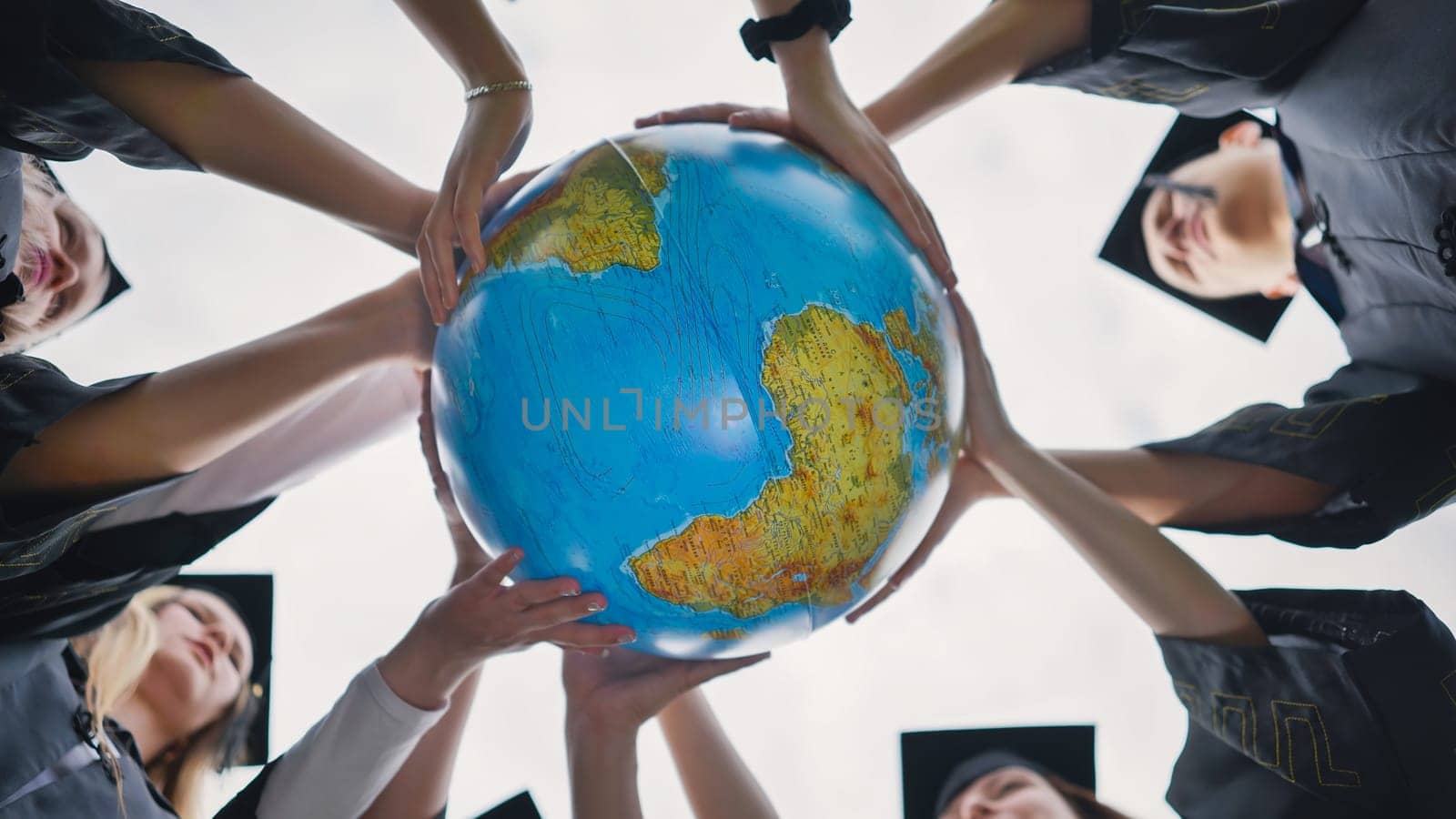 Graduating students twirl a geographic globe of the world in their hands