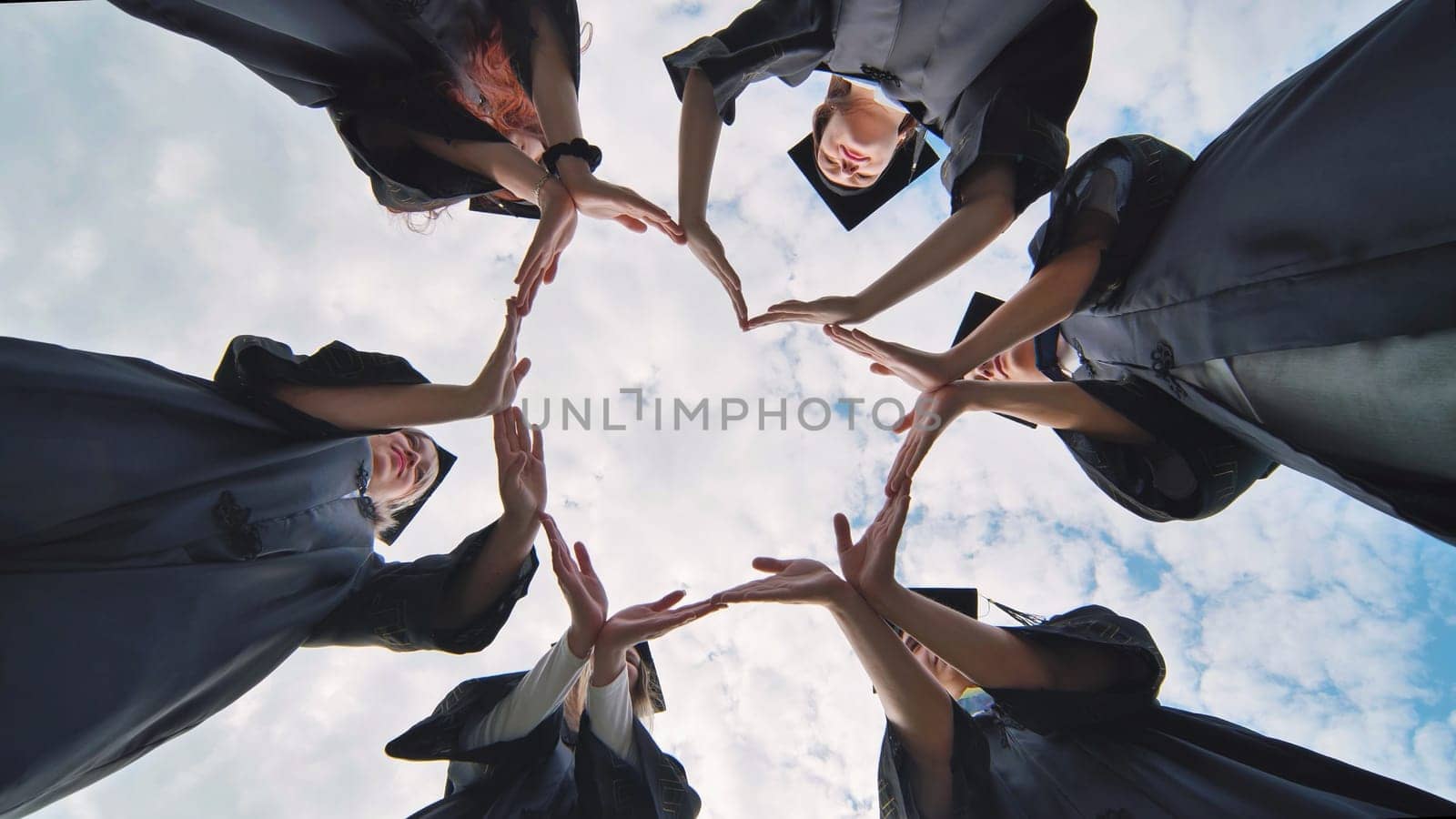 Students graduating from the college make a heart out of their hands. by DovidPro