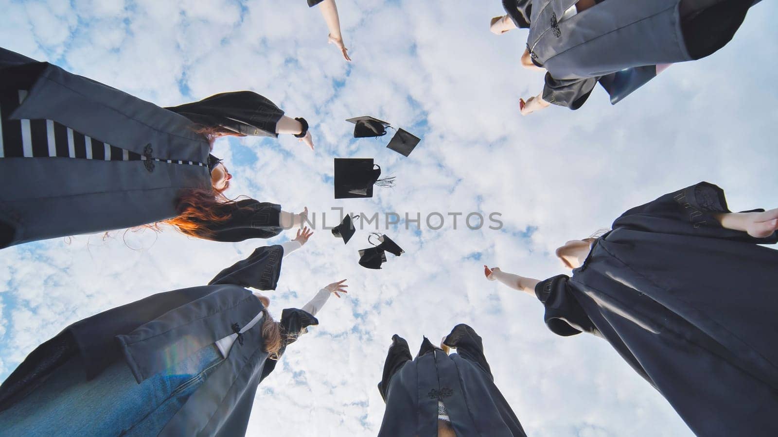 Silhouettes of Happy college graduates tossing their caps up at sunset.