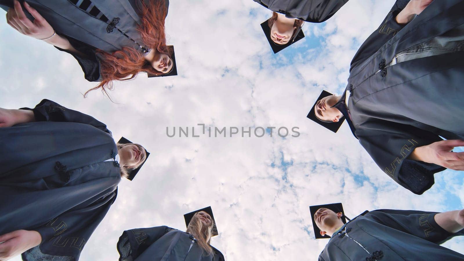 College students stand in a circle wearing black robes. by DovidPro