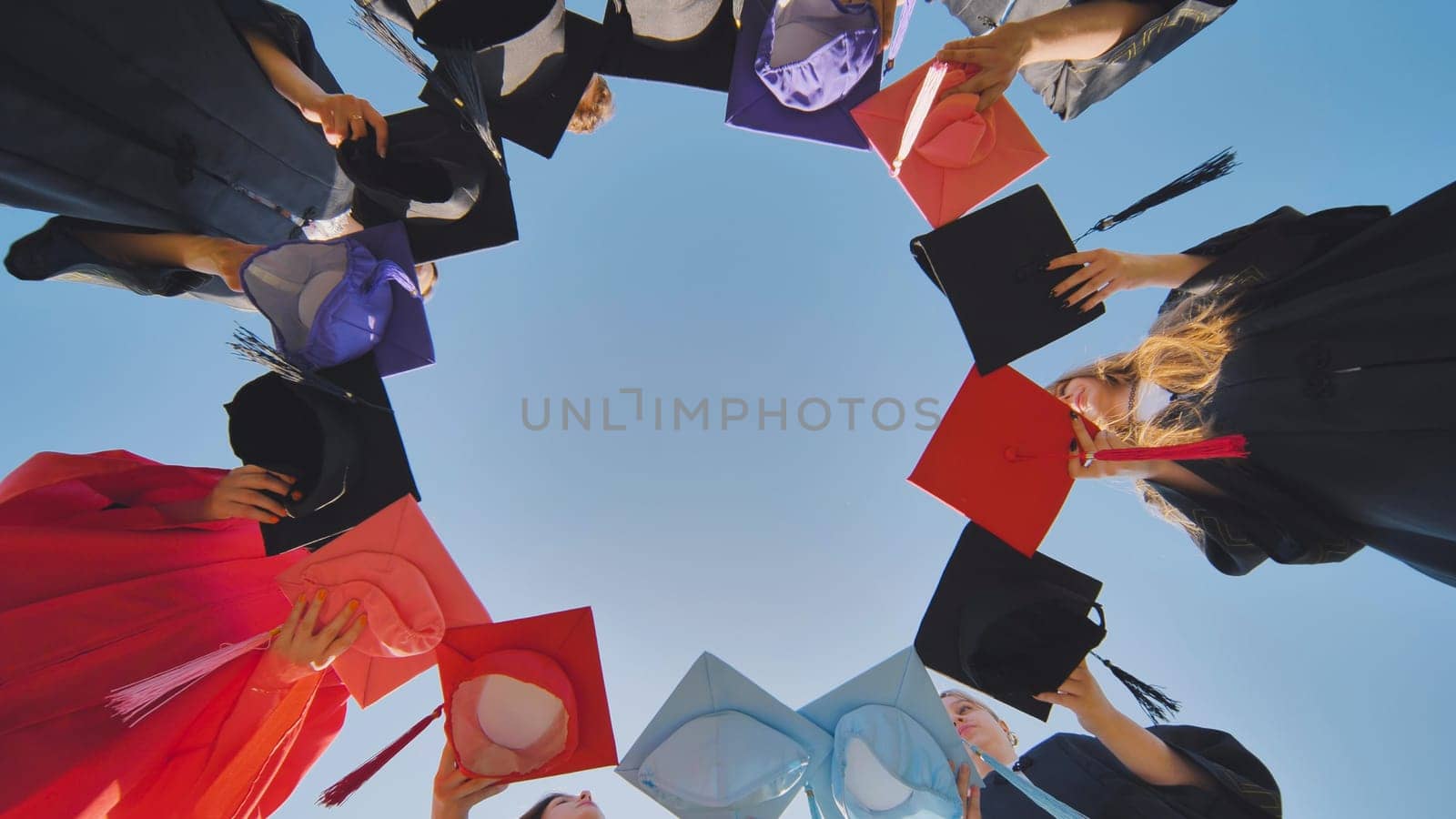 College graduates make a circle shape out of their colorful hats