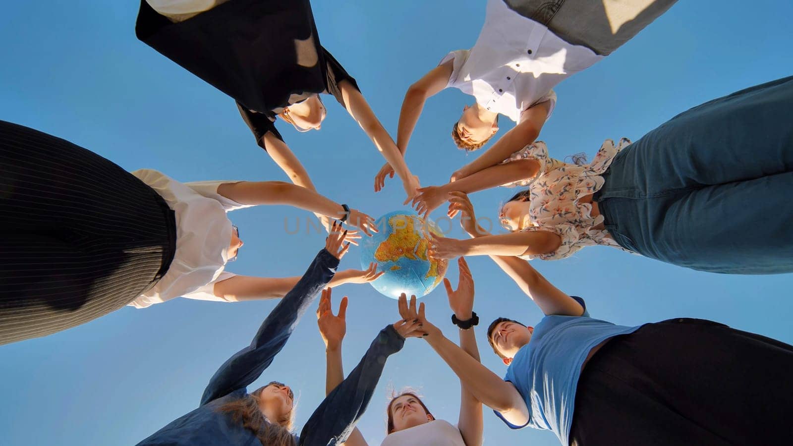 Friends hold and toss a geographic globe in their hands. The concept of keeping the world safe