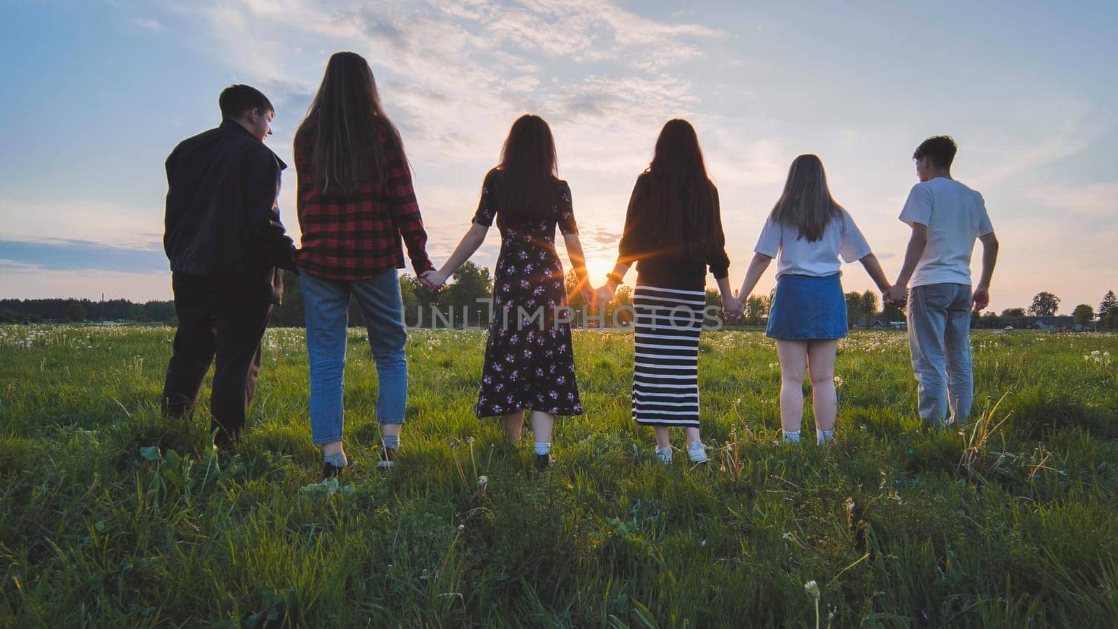 A group of friends stand in a row at sunset