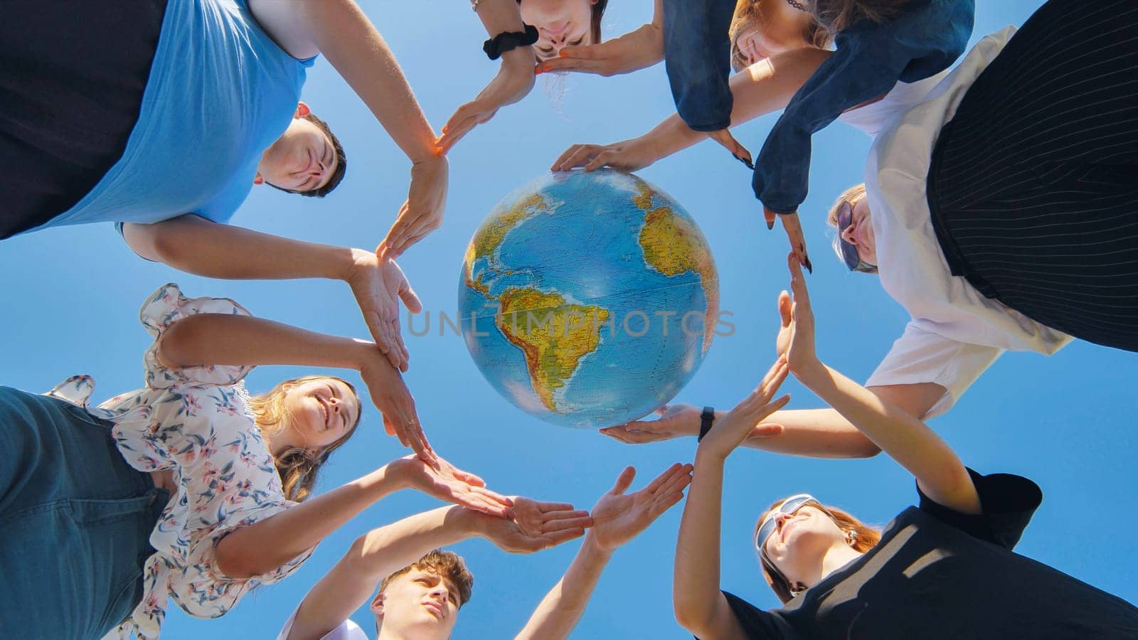 Students make a circle around the globe of the world. The concept of world peace. by DovidPro