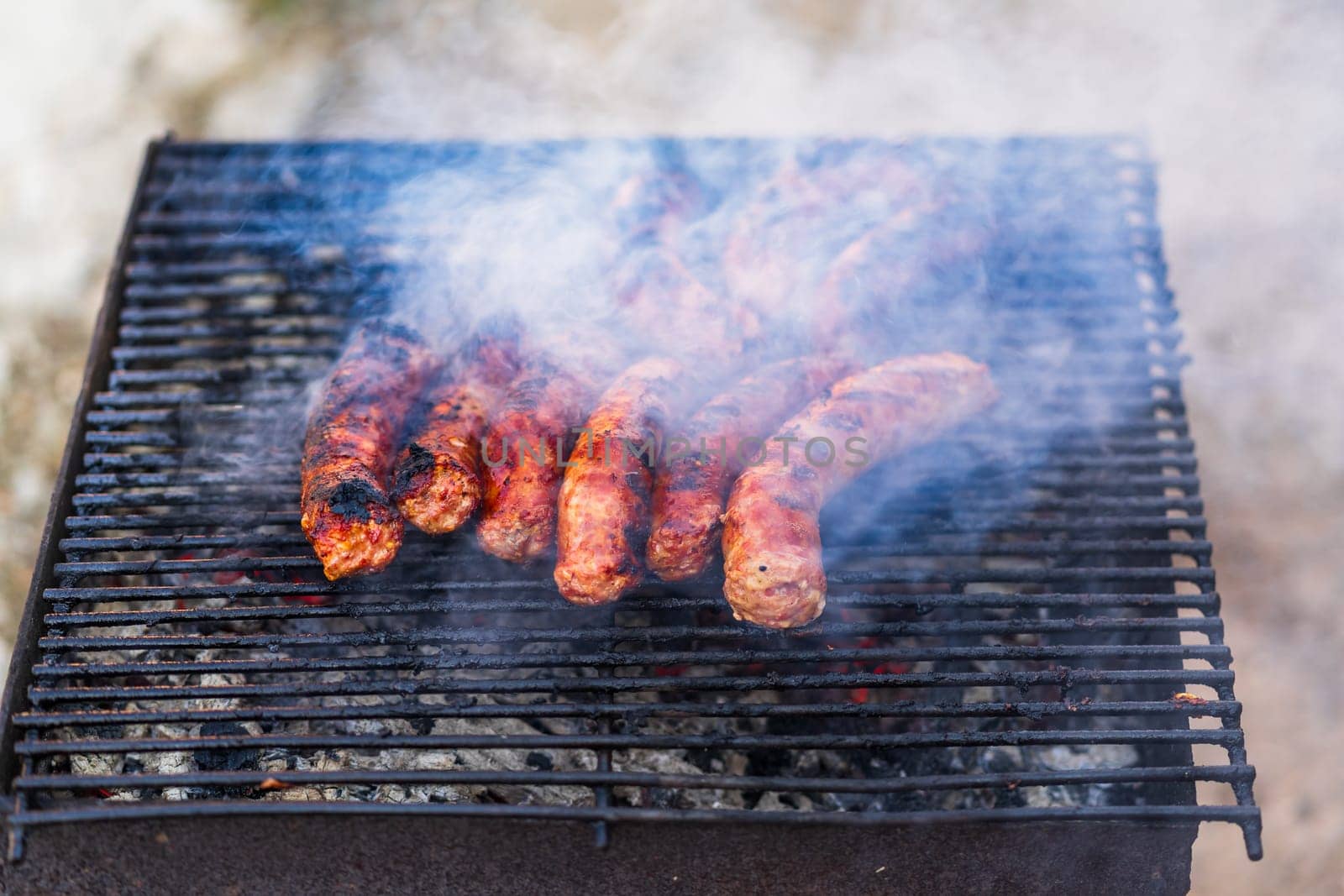 Grilling sausages on barbecue grill. Delicious sausages on charcoal grill