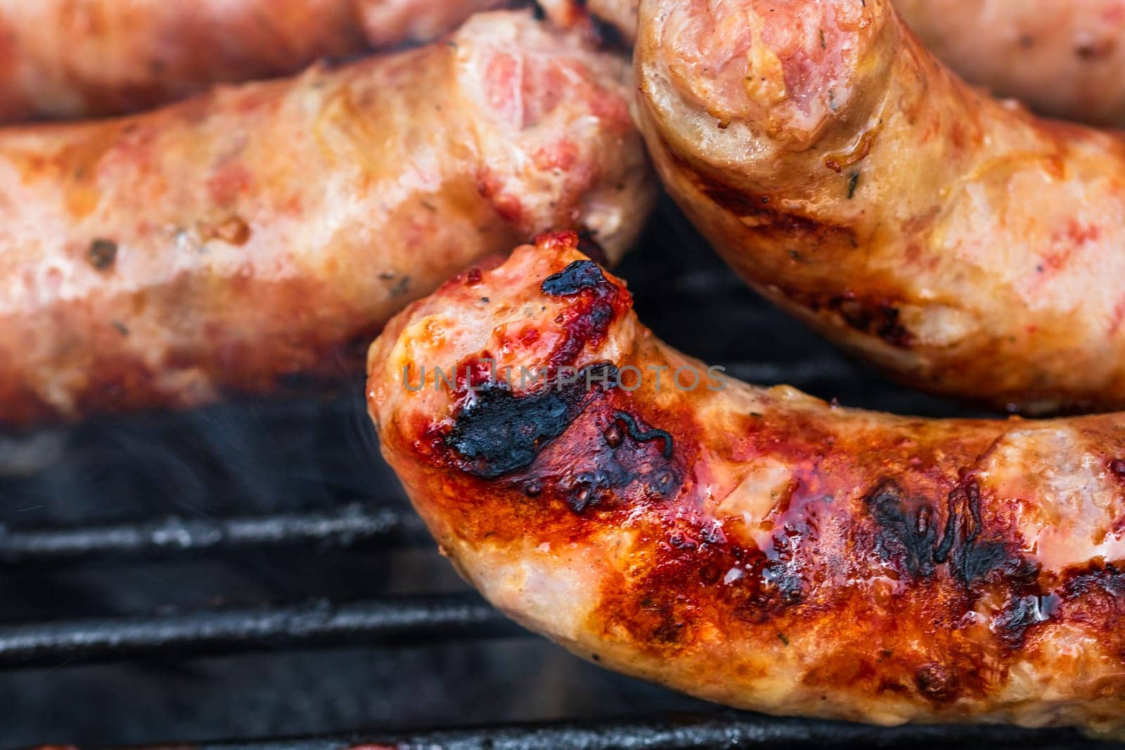 Close up on details of homemade sausages on barbecue grill. Barbecue, grill and food concept.