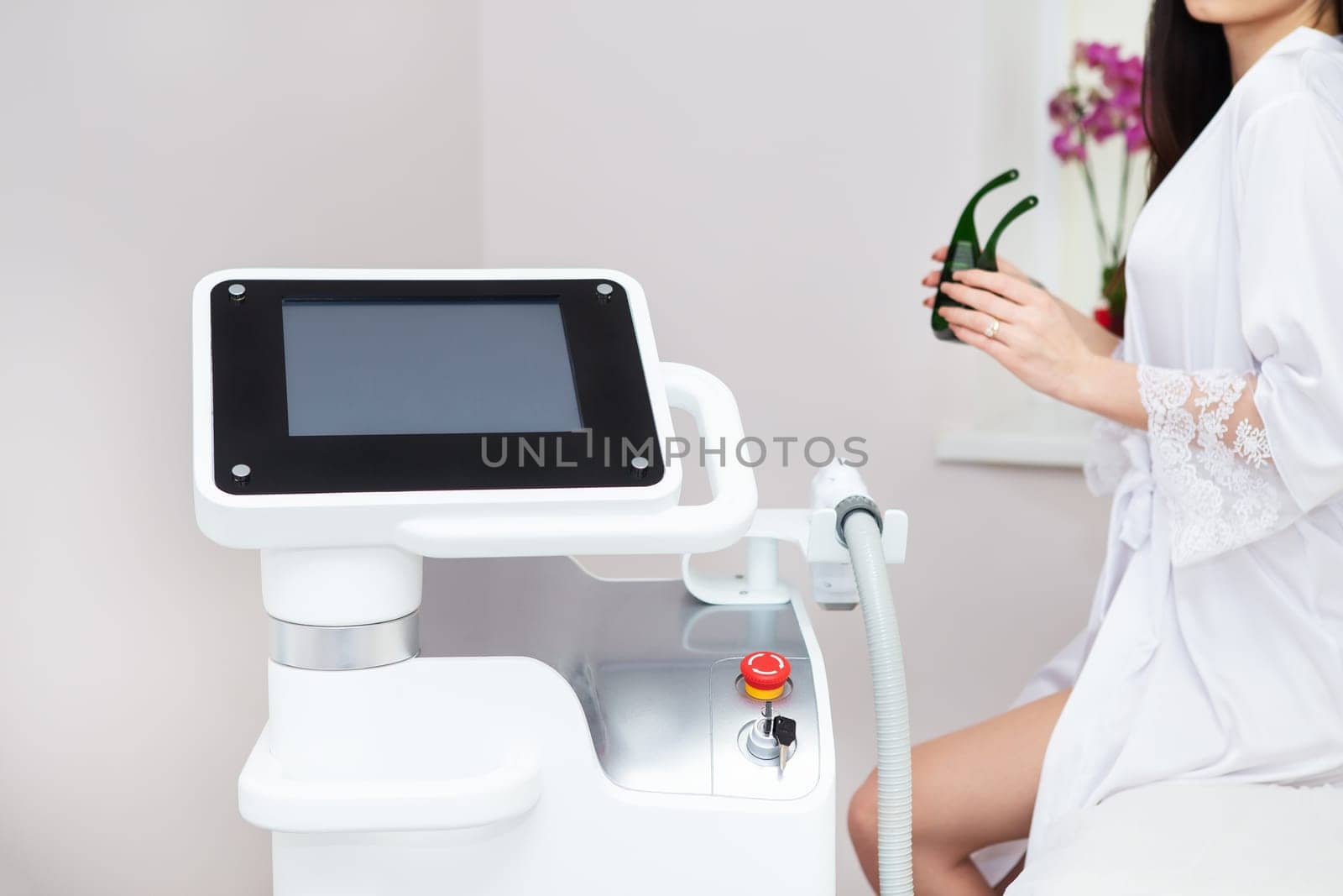 Professional laser hair removal machine, screen for setting up the hair removal process. Professional cosmetology, body epilation. Body care concept, client in the background. by sfinks