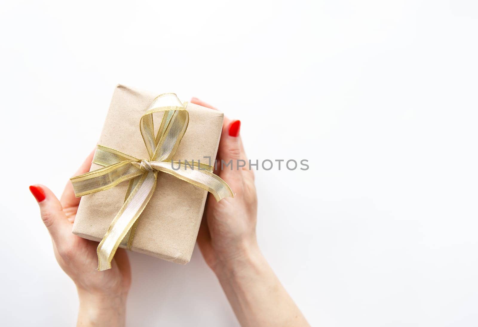 Gift box wrapped in gold ribbon in hand isolated on white. Surprise and holiday concept