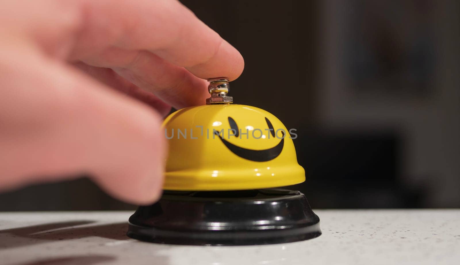 man using a yellow smiley hotel bell. ringing service bell