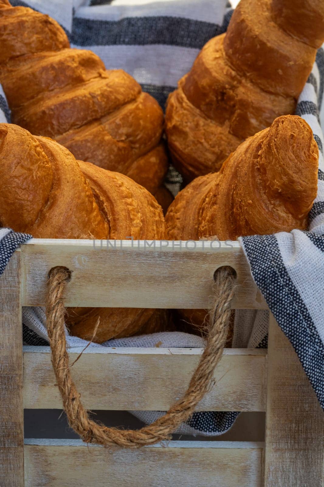Fresh croissant, puff pastry and buttered french croissant on wooden crate. Food and breakfast concept. Detail of desserts and fresh pastries by vladispas