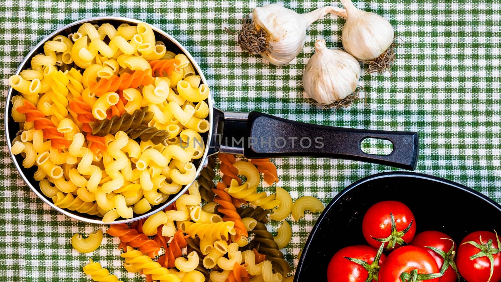 Small mini frying pan with tricolor raw fusilli pasta in a rustic composition.