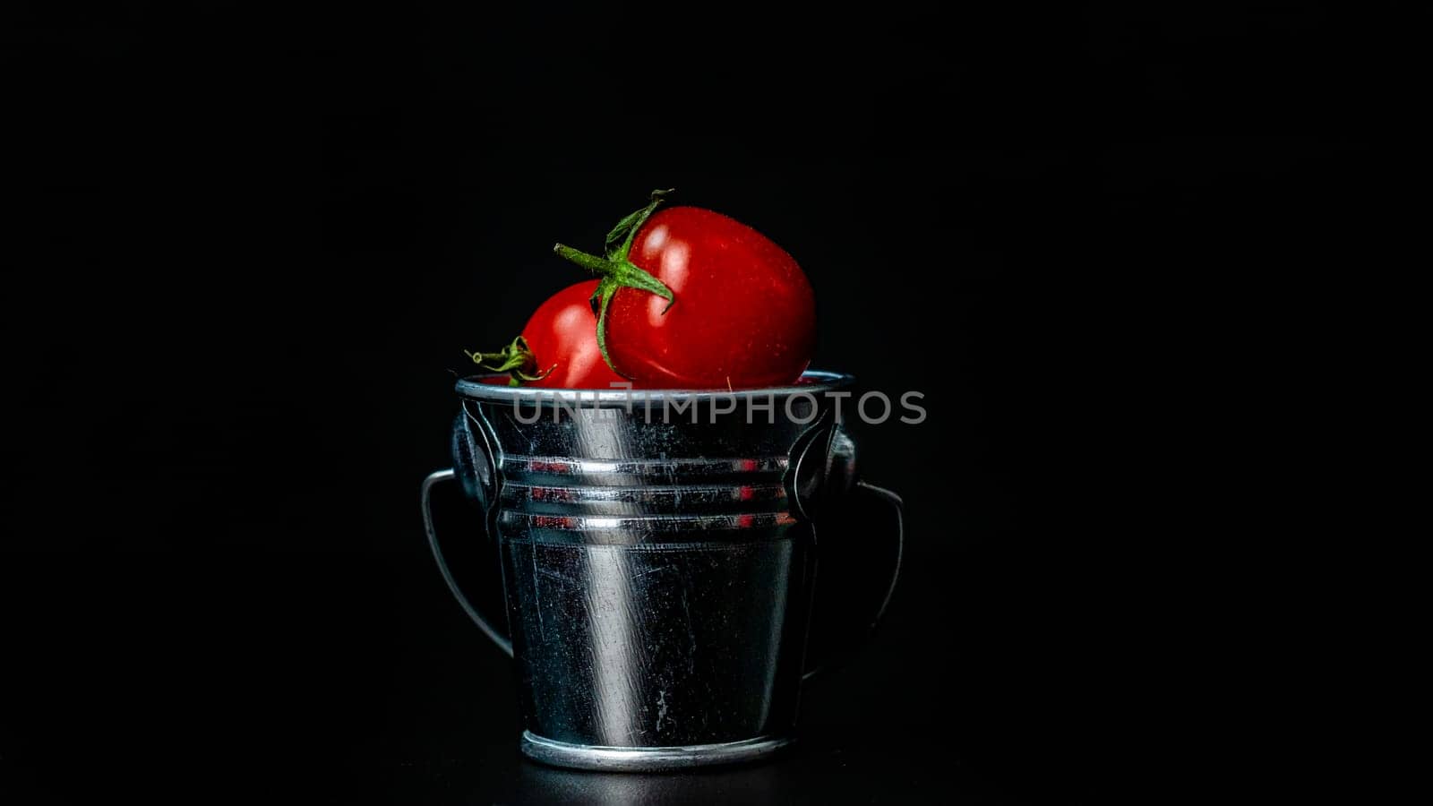 Selective focus on composition with mini decorative bucket and tomatoes. Small metal bucket with cherry tomatoes