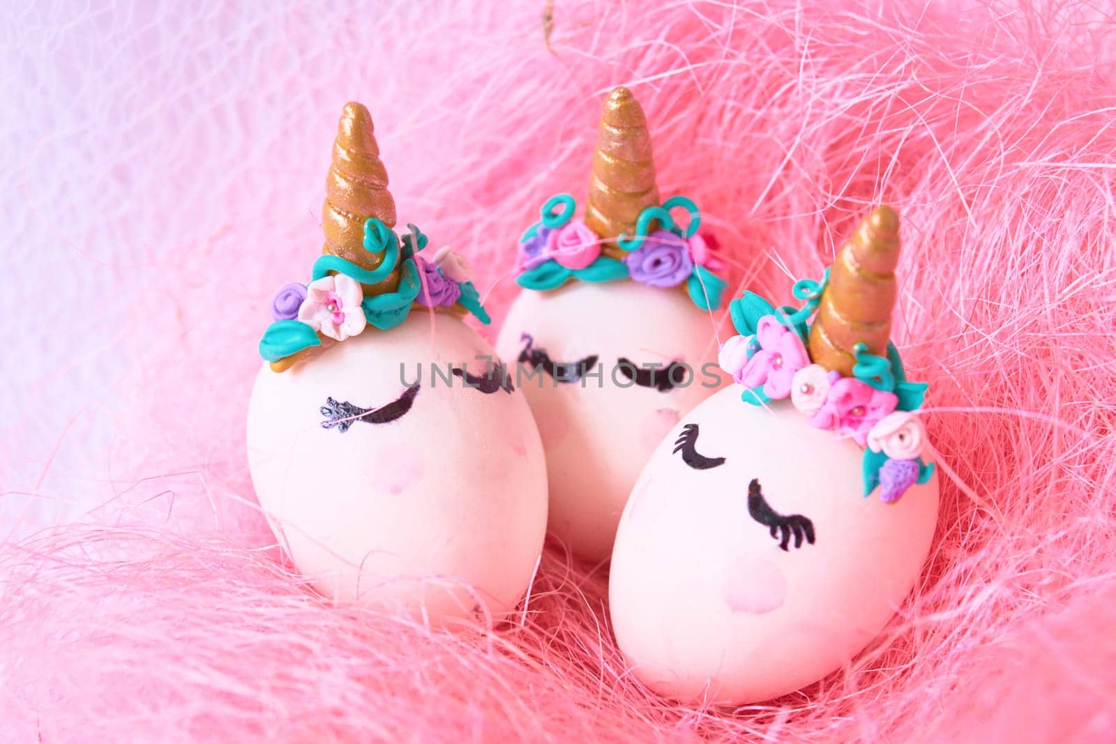 Three Easter eggs unicorns in a pink nest