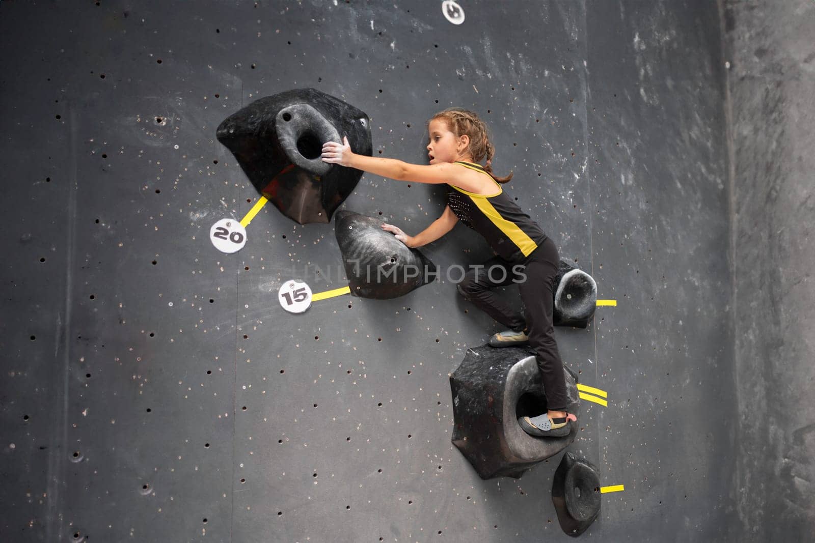 Little girl trained climbs wall in climbing centre by andreonegin