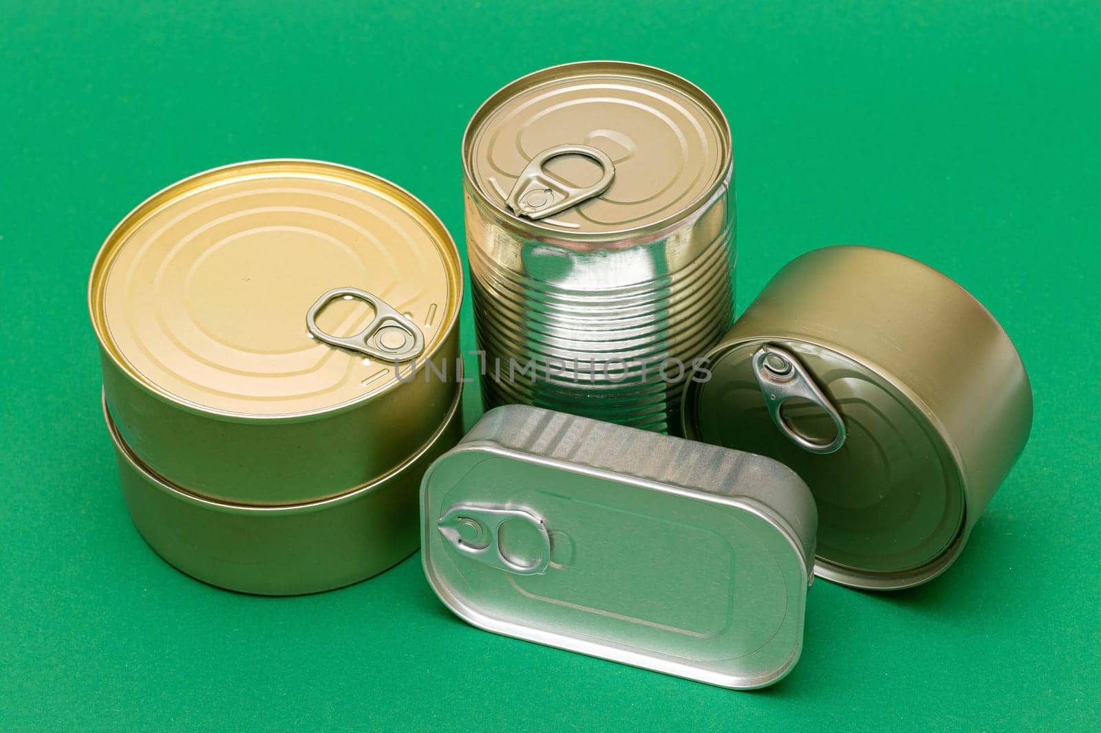 A Group of Stacked Tin Cans with Blank Edges on Green Background. Canned Food. Different Aluminum Cans for Safe and Long Term Storage of Food. Steel Sealed Food Storage Containers